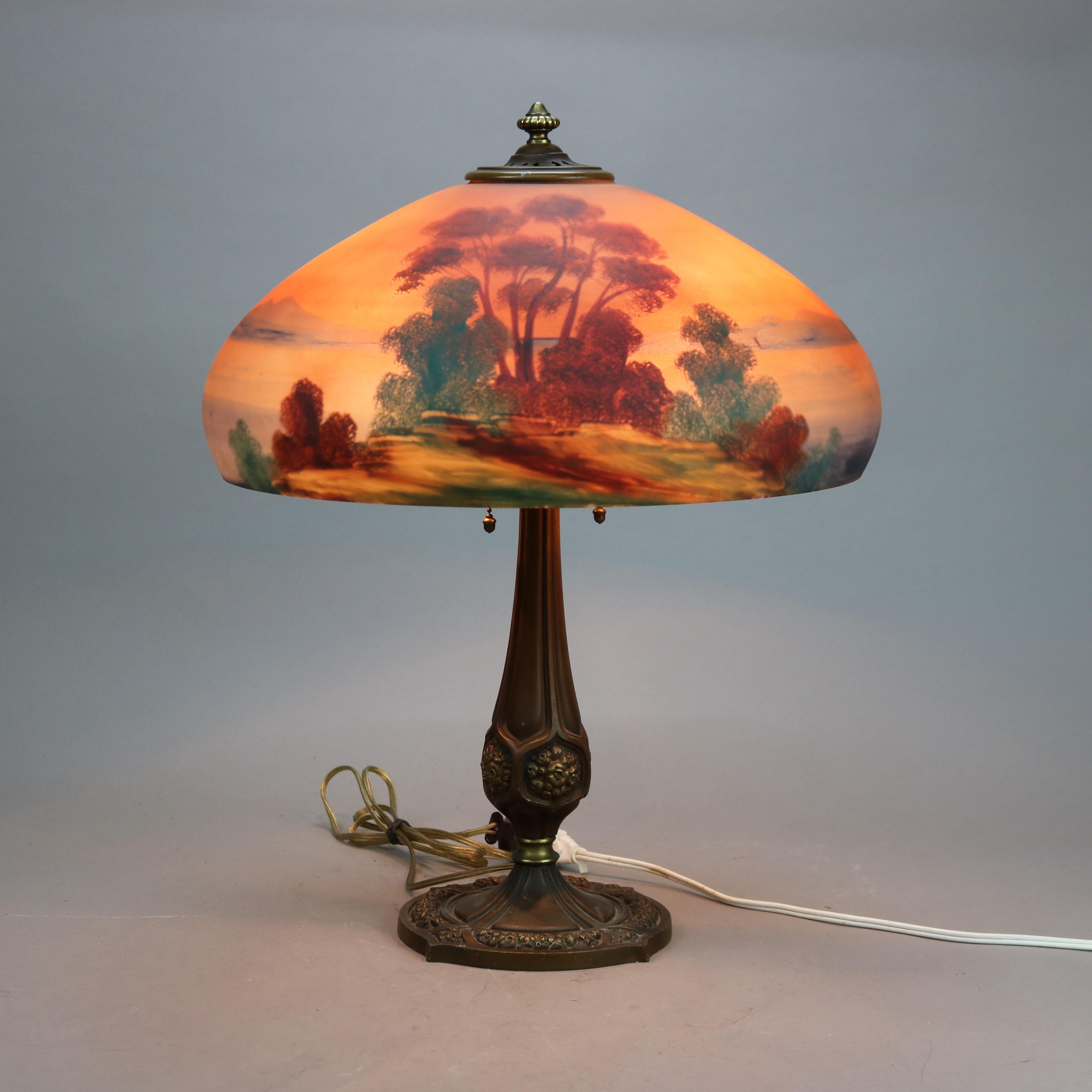 An antique Arts and Crafts table lamp by Pittsburgh Lamp Co offers dome shade having reverse painted landscape scene with lake over double socket base, c1920

Measures - 22''H x 17.5''W x 17.5''D.