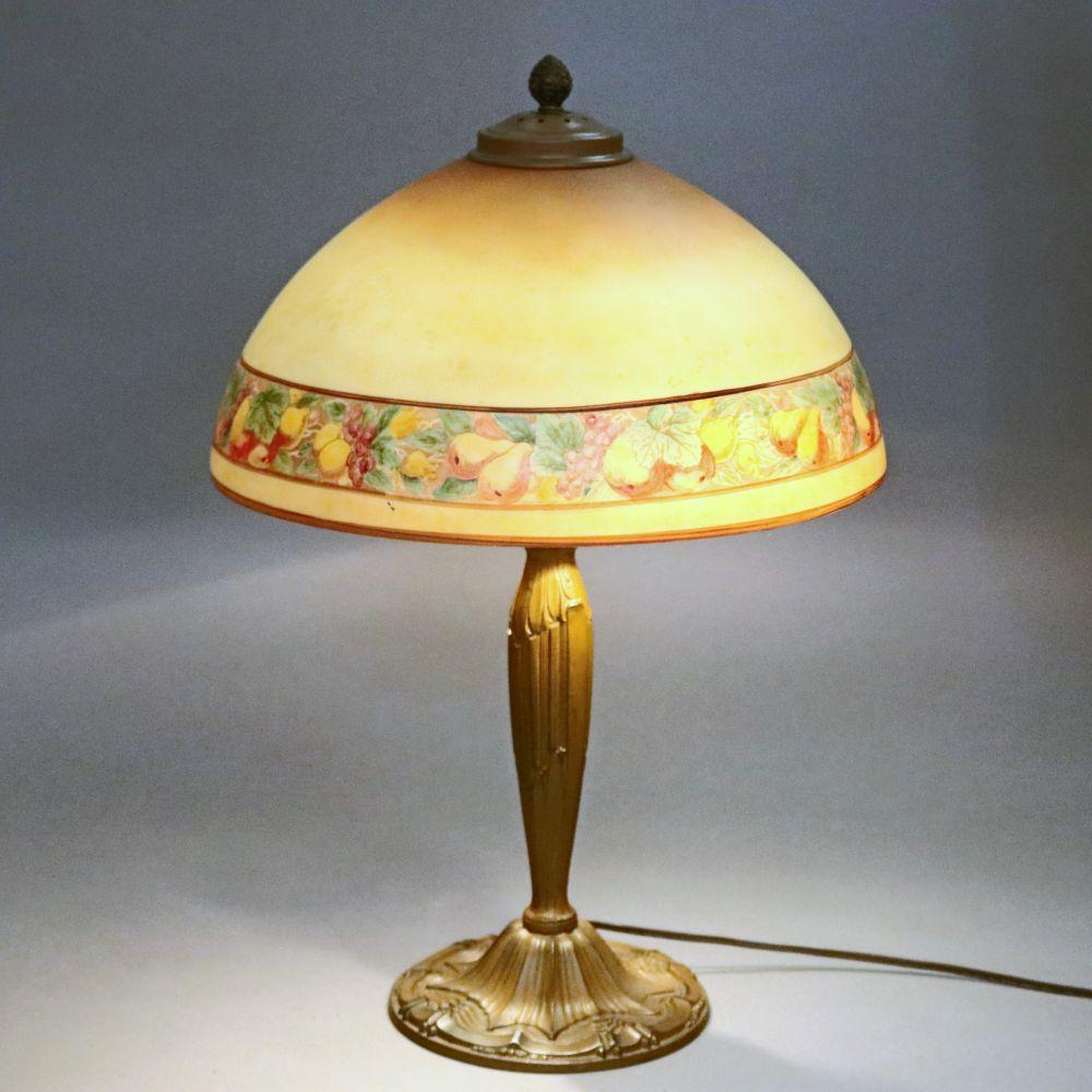An antique Arts & Crafts Pittsburgh School table lamp in the manner of E. Miller & Co. offers cast bronze base having Dual independently controlled sockets, is embossed with maker, and surmounted by a reverse painted glass dome form shade with still