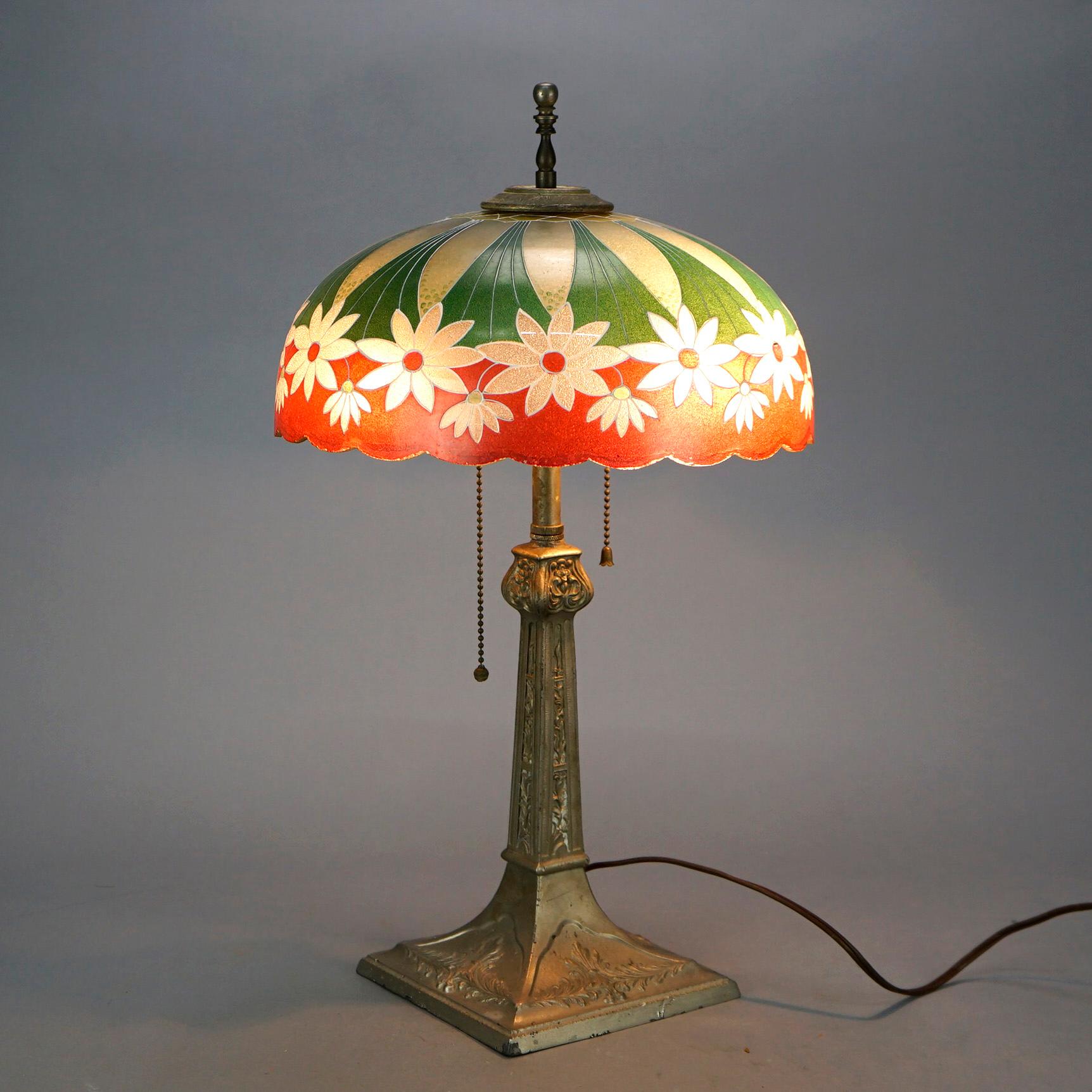 An antique Arts and Crafts table lamp in the manner of Pittsburgh Lamp Co offers glass dome form shade decorated with repeating pattern of daisies and scalloped rim over cast double socket base having embossed foliate elements, c1920

Measures-