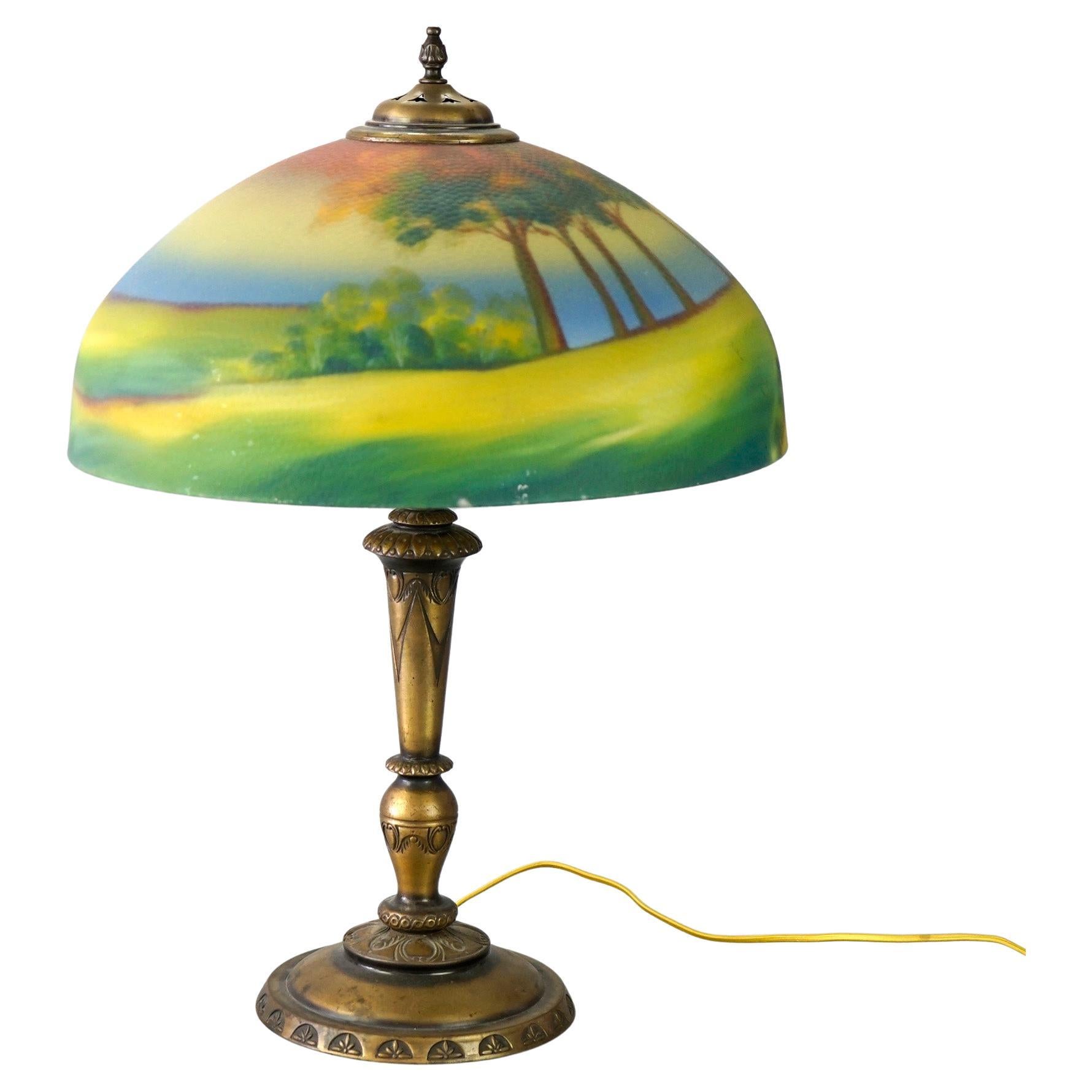An antique Arts and Crafts table lamp in the manner of Pittsburgh Lamp offers reverse painted shade having landscape scene over double socket cast base, c1920

Measures- 23.5''H x 16.5''W x 16.5''D.