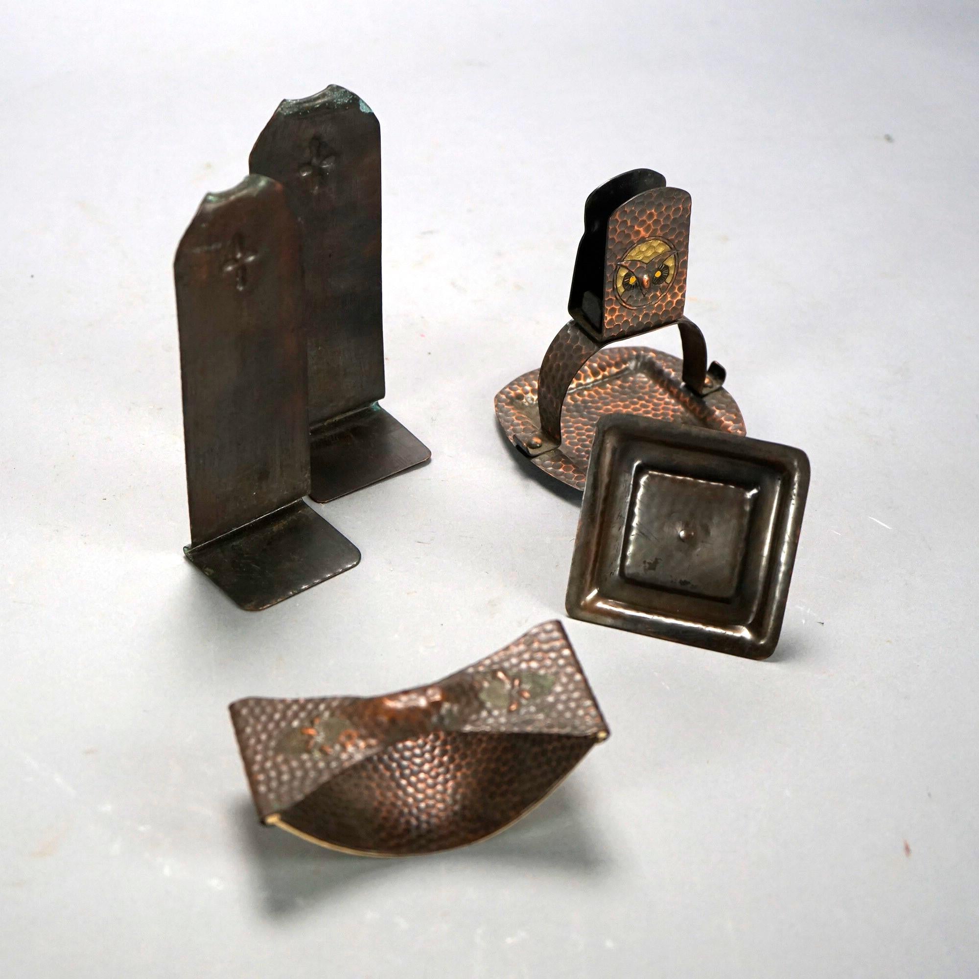 An antique Arts and Crafts desk set in the manner of Roycroft offers hammered copper construction with polychromed owl and cross as photographed, c1910

Measures- 
Ink press: 2''H x 4.5''W x 2''D
Candle holder: 1.75''H x 3''W x 3''D
Bookends: 6''H x