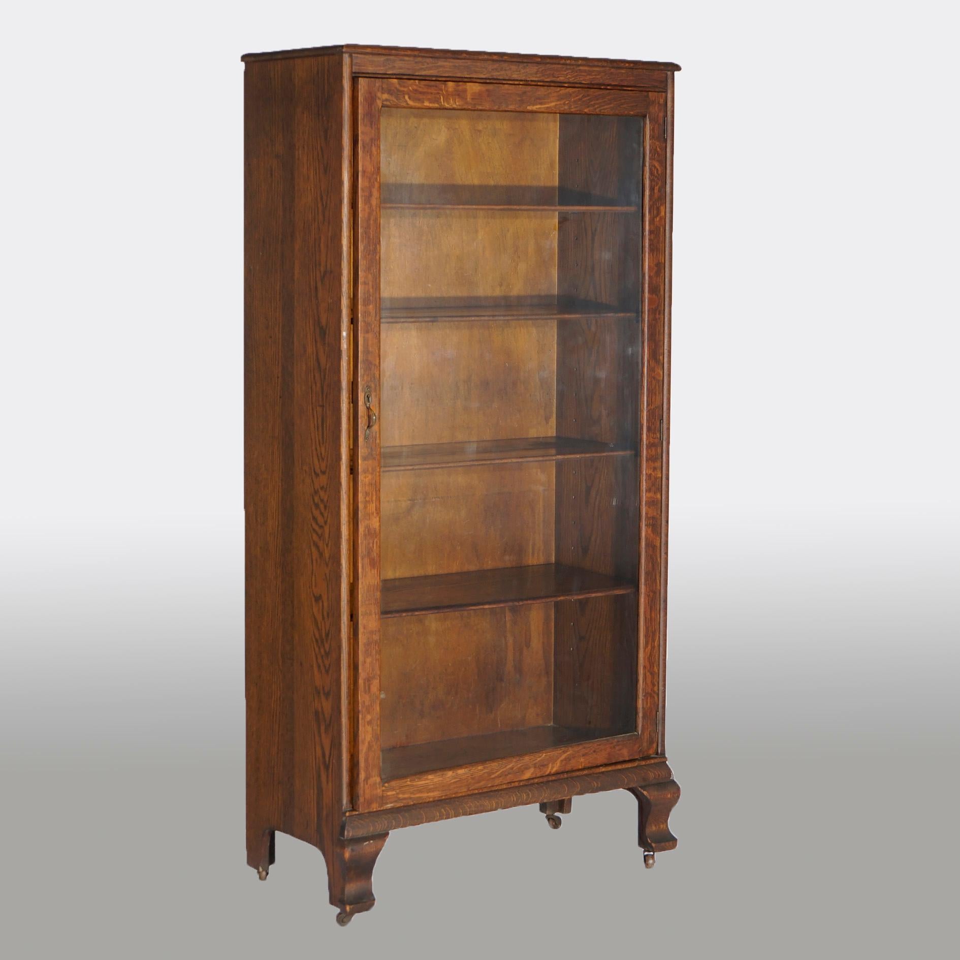 An antique Arts & Crafts enclosed bookcase offers quarter sawn oak construction with single glass door opening to adjustable shelf interior and raised on stylized cabriole feet, c1920.

Measures- 60''H x 29.25''W x 14.5''D.

Catalogue Note: Ask