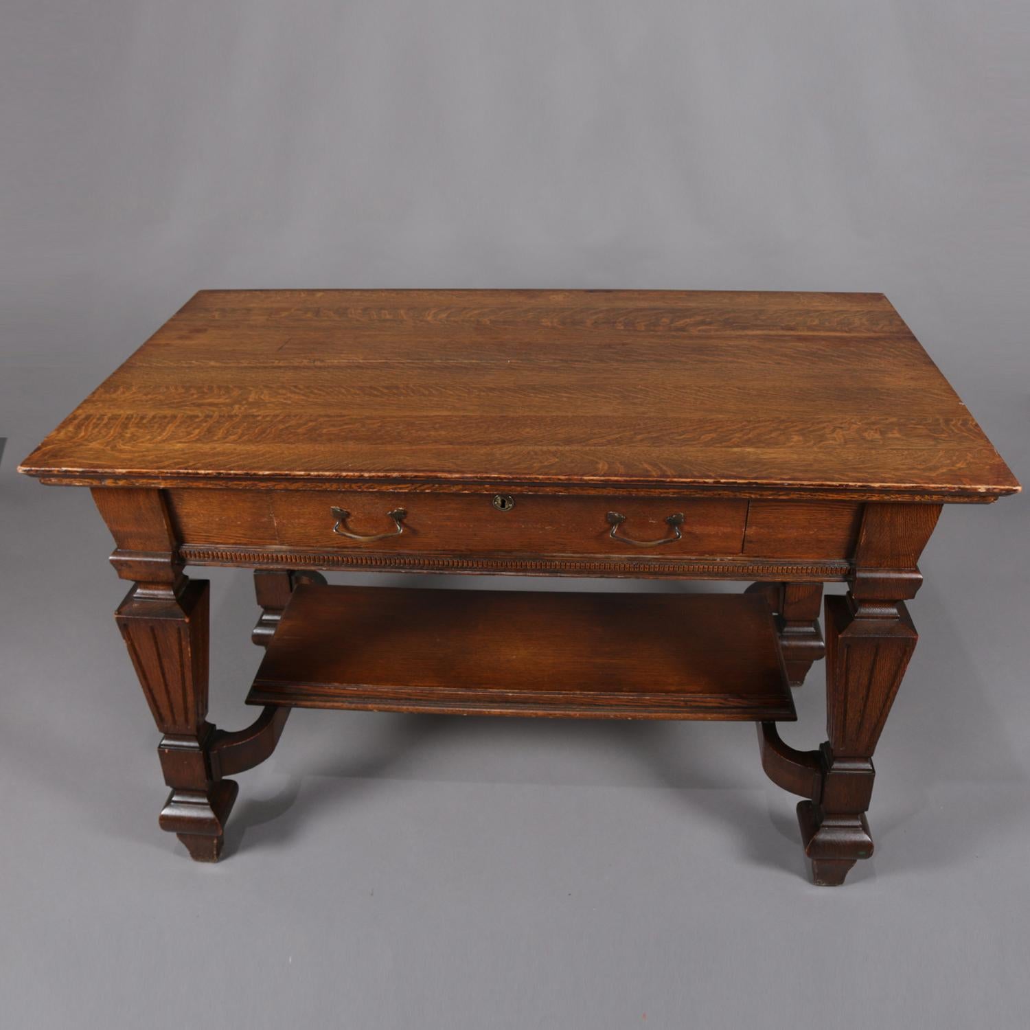Antique Arts & Crafts R. J. Horner School Oak horner school library table features quarter sawn oak construction with flared cabinet having single drawer above reeded square and flared columnar supports with stretcher having lower shelf, circa