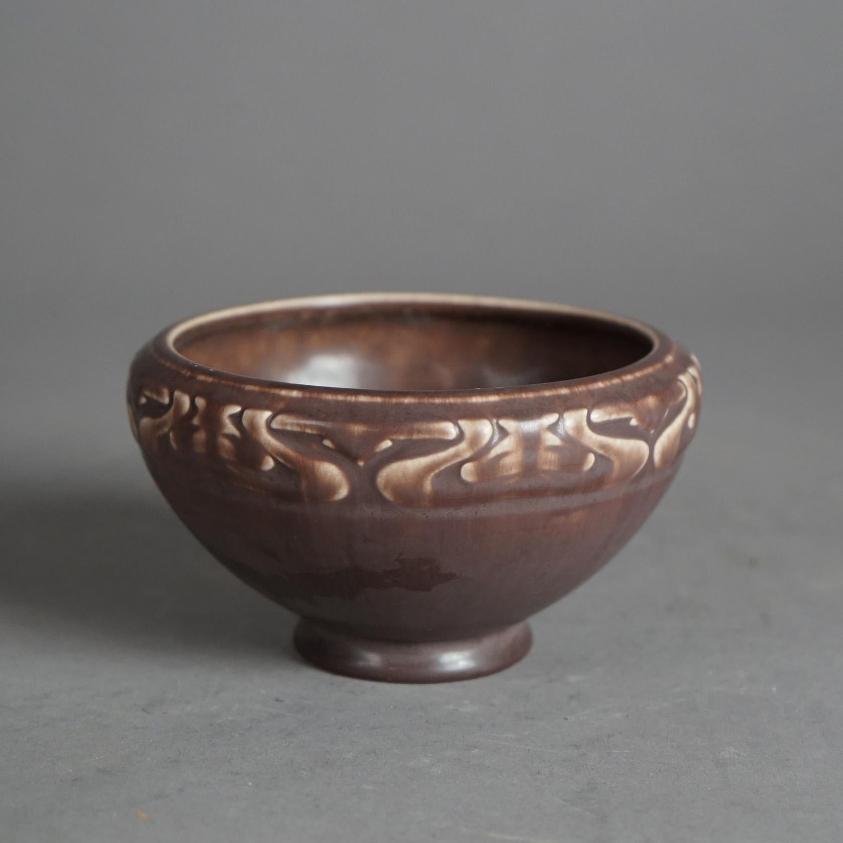 An antique Arts and Crafts bowl by Rookwood offers tapered form with stylized foliate band and maker mark on base as photographed, c1921

Measures- 3''H x 5.25''W x 5.25''D