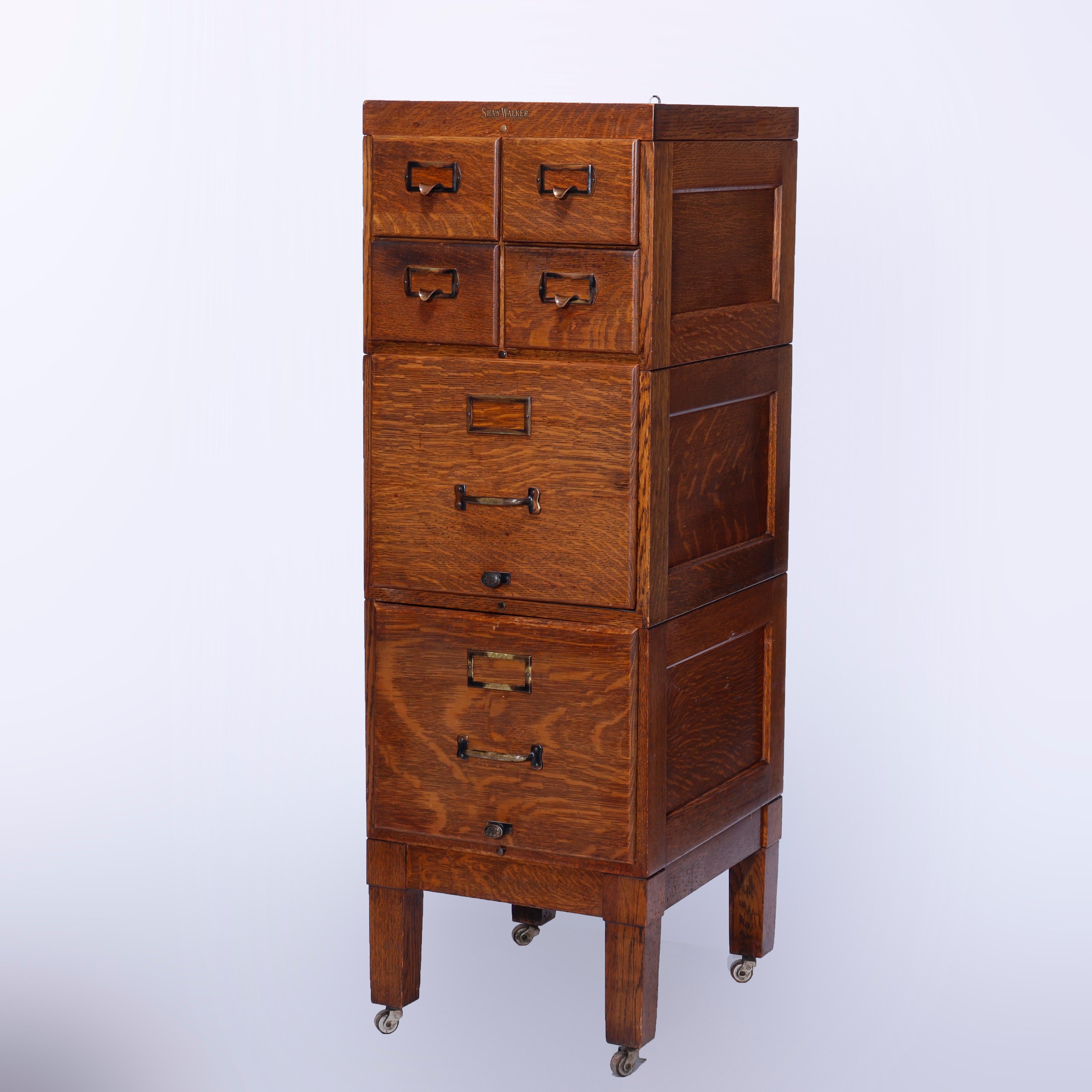 An antique Arts and Crafts filing cabinet by Shaw Walker Oak offers paneled quarter sawn oak construction with three sections including one card catalog and two standard files, raised on straight and square legs, make label at top as photographed,