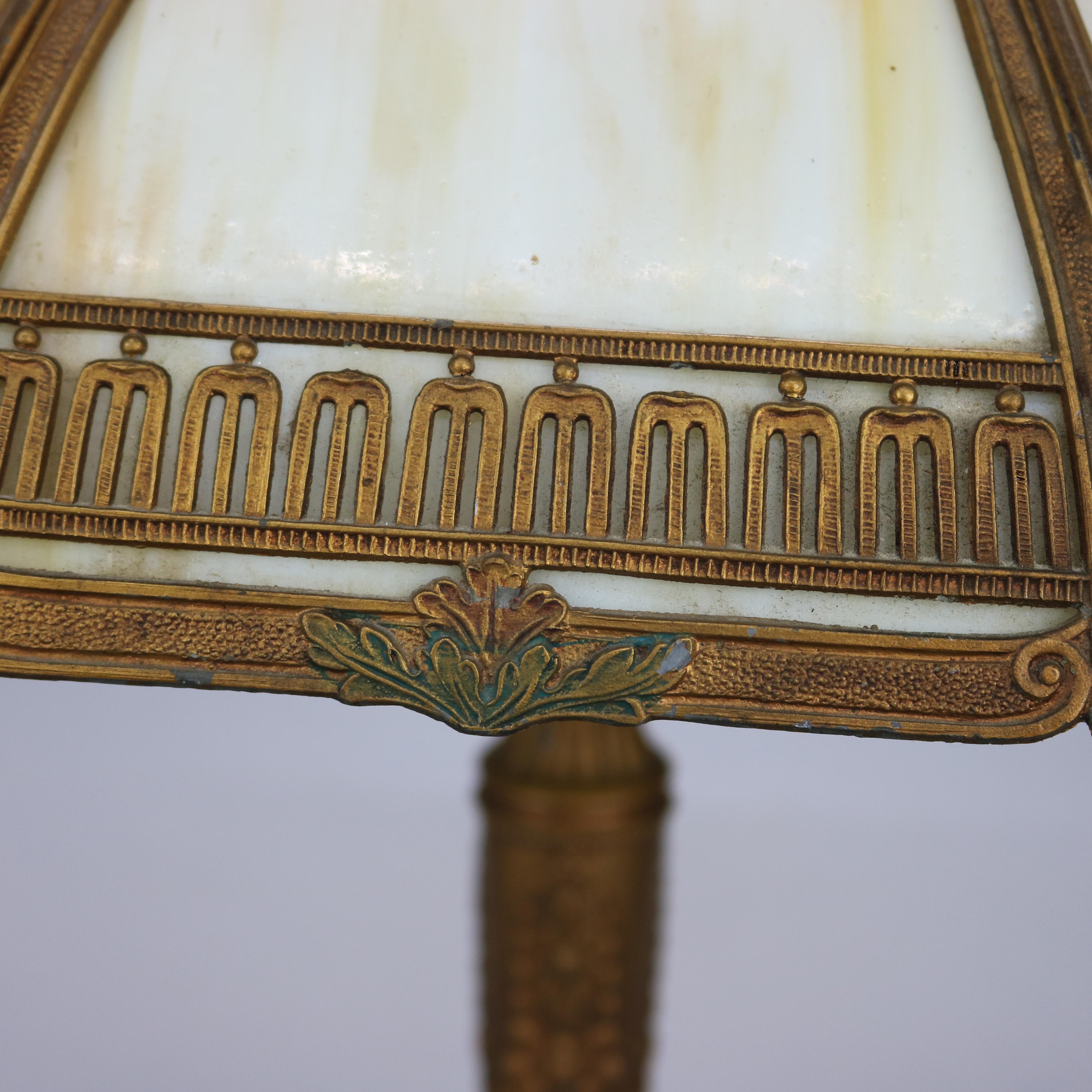 An Arts and Crafts table lamp in the manner of Bradley and Hubbard offers domed filigree shade housing bent slag glass panels over double socket base having urn form with floral relief, c1920

Measures: 22.25