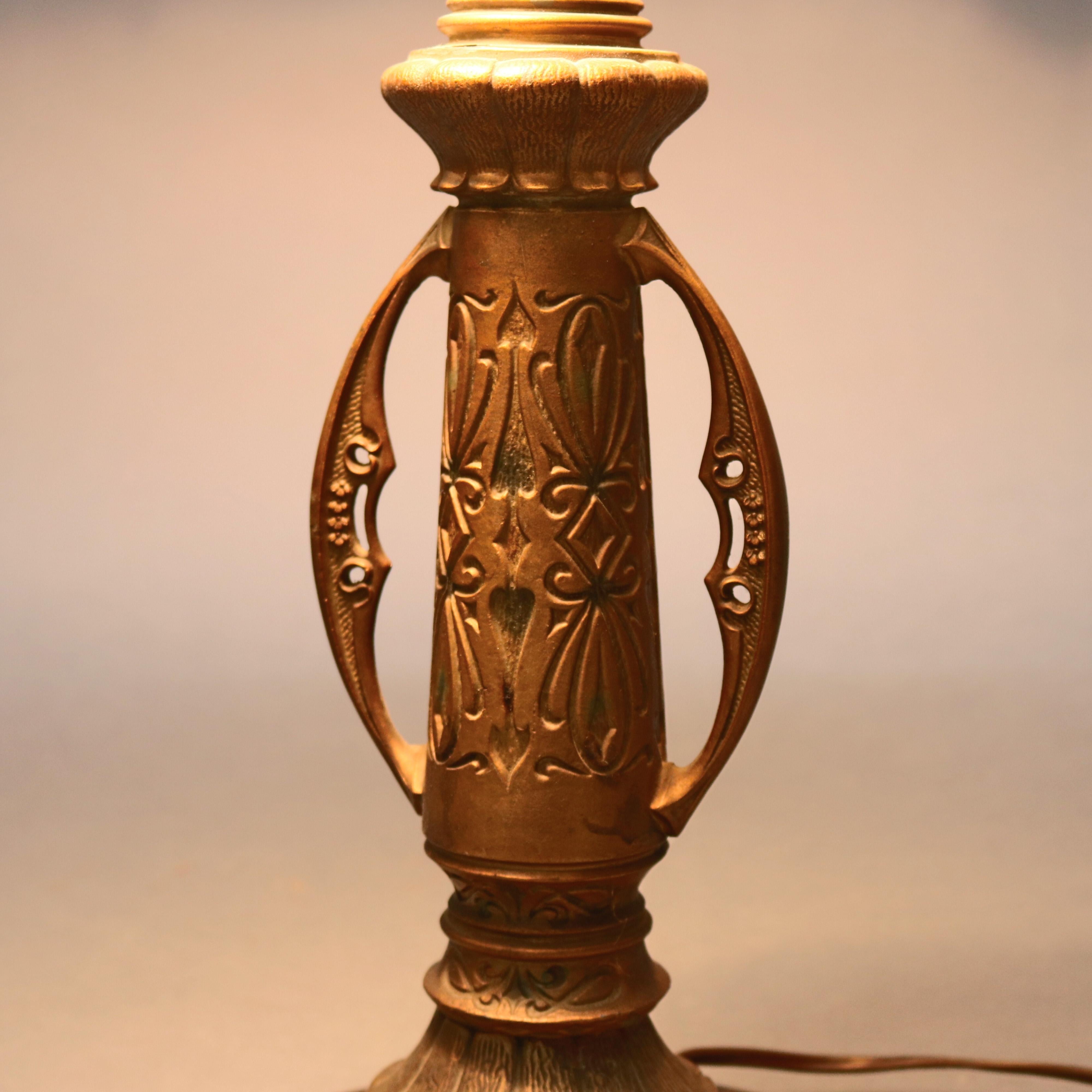 Antique Arts and Crafts era Bradley & Hubbard table lamp features stylized urn form double socket cast base with incised floral motif, dome form shade with cast filigree shade having foliate garland and wreath decoration and six bent slag glass