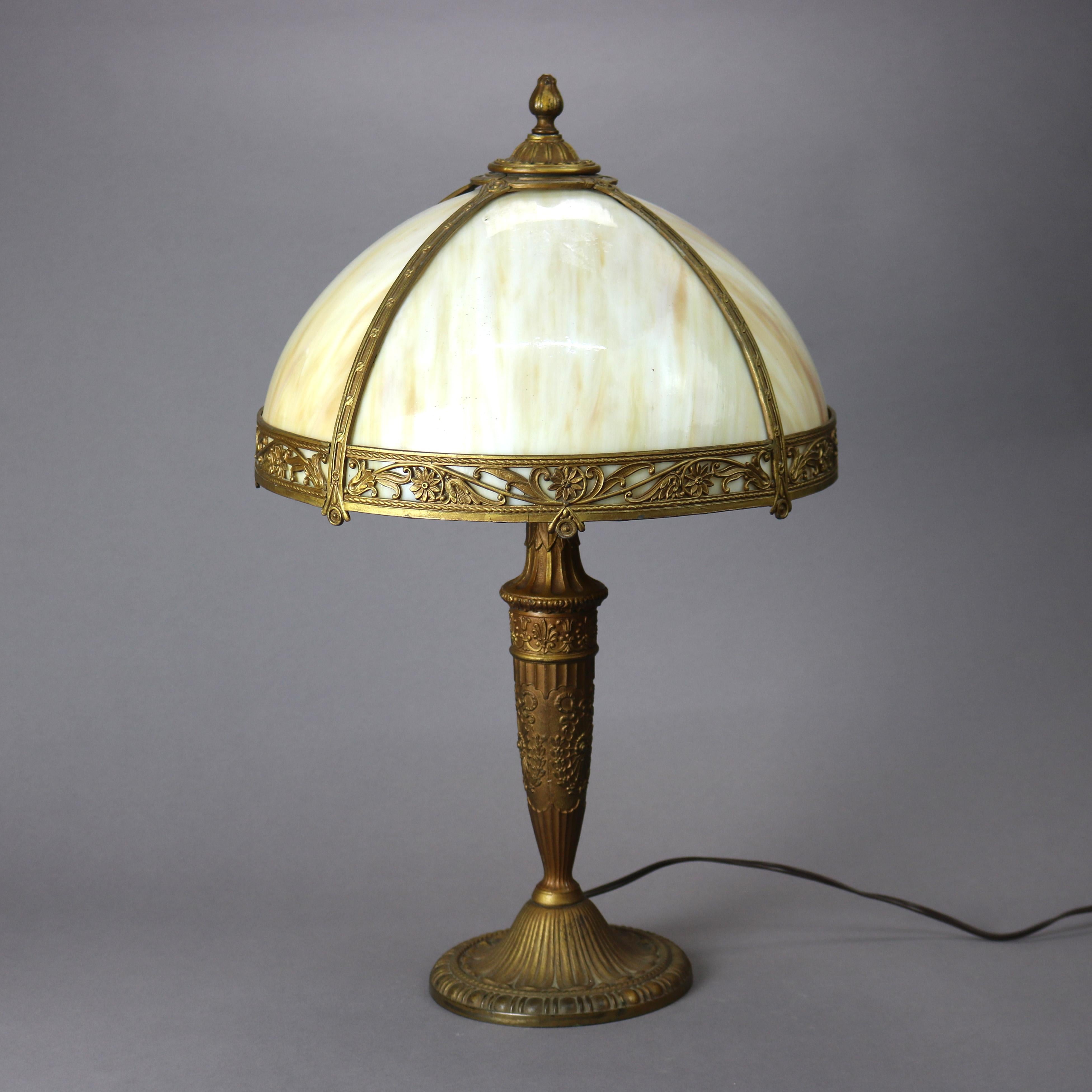 An antique Arts and Crafts table lamp offers dome form shade with cast shade having pierced floral band and housing bent slag glass panels over single socket cast base, circa 1920

Measures - 22.75