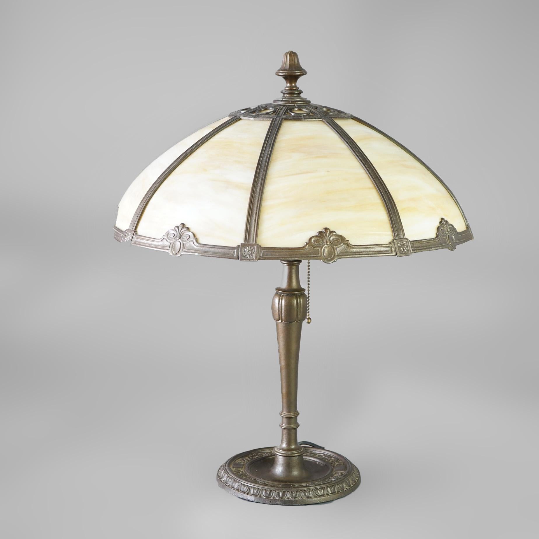 An antique Arts & Crafts table lamp offers dome form shade with frame having stylized floral elements and housing bent slag glass panels, over double socket cast base, c1920

Measures - 23