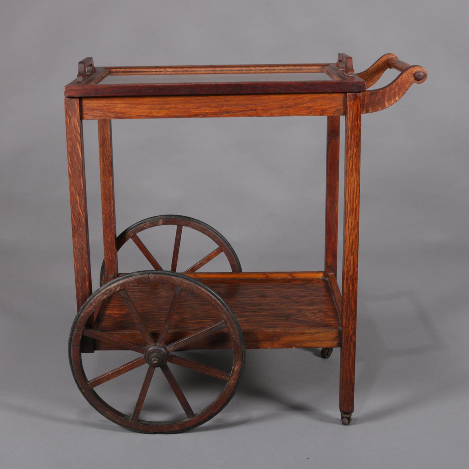 Antique Arts & Crafts Stickley Brothers tea cart features Mission Oak construction and design with upper and lower tray, scrolled handle, oversized and spoked wheels, 