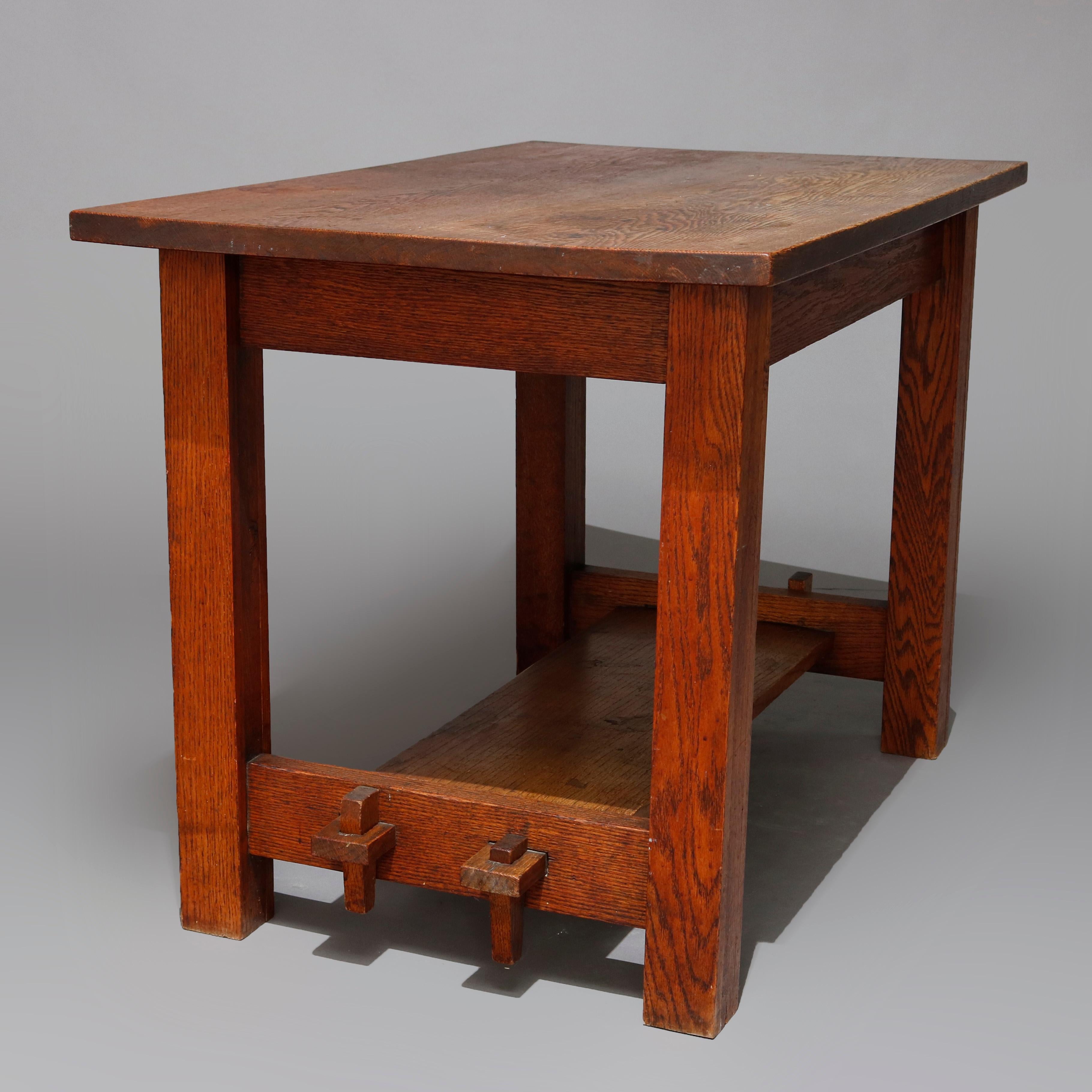 An antique Arts & Crafts Stickley Bros. School mission oak library table offers work surface supported by pegs and raised on square and straight legs having lower mortise and tenon shelf, circa 1910

Measures: 29.75