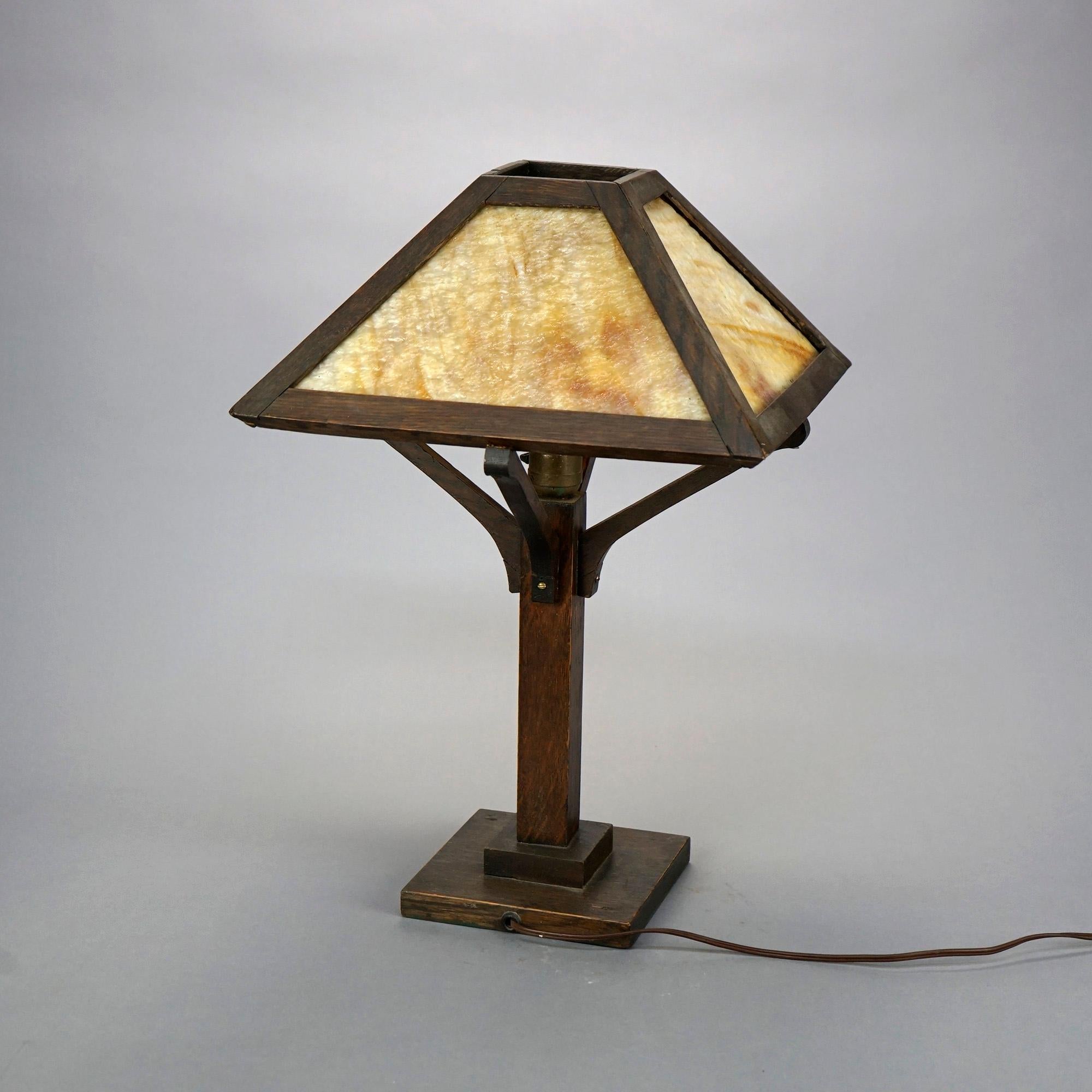 An antique Arts and Crafts table lamp in the manner of Stickley Prairie offers oak frame with slag glass shade, c1910

Measures- 21''H x 14''W x 14''D.