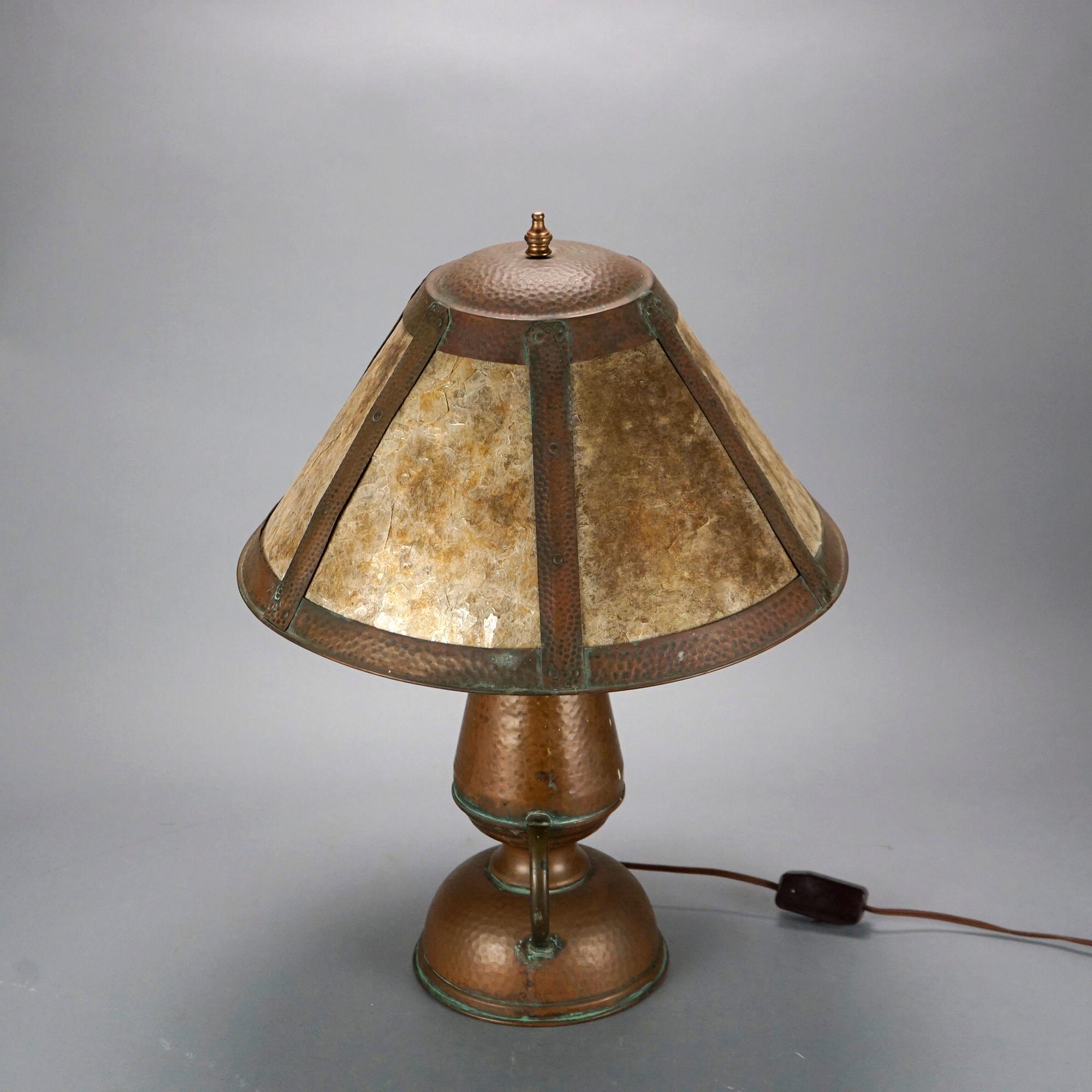 An antique Arts and Crafts table lamp in the manner of Stickley offers hammered mica shade over hammered copper double handle urn form base having two sockets, c1920

Measures- 21.75''H x 16.25''W x 16.25''D