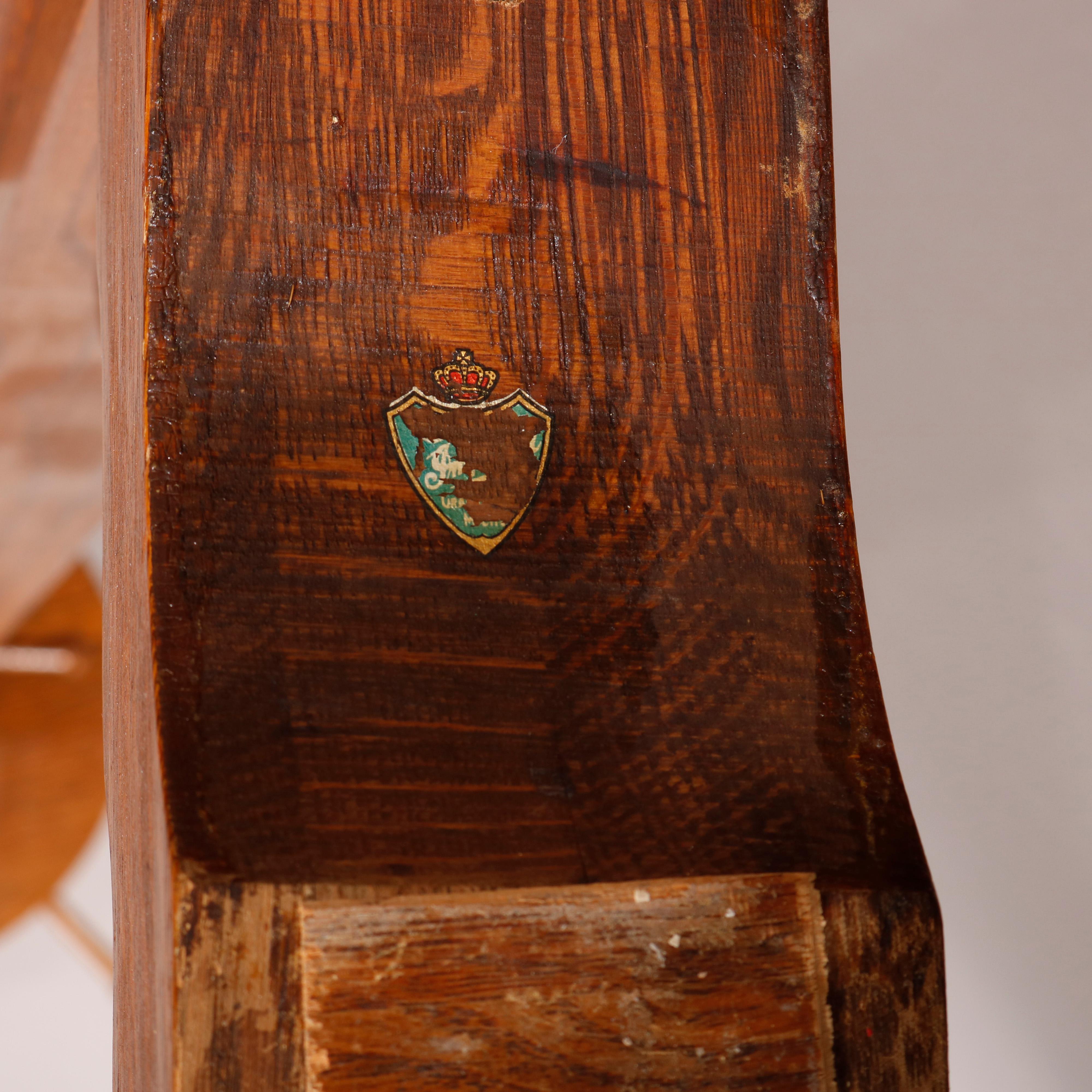 An antique Arts & Crafts hall tree in the manner of Stickley offers oak construction with rotating circular garment hanger having spindle pegs over flared base with quadruped base having corbels, partial original shield and crown label as