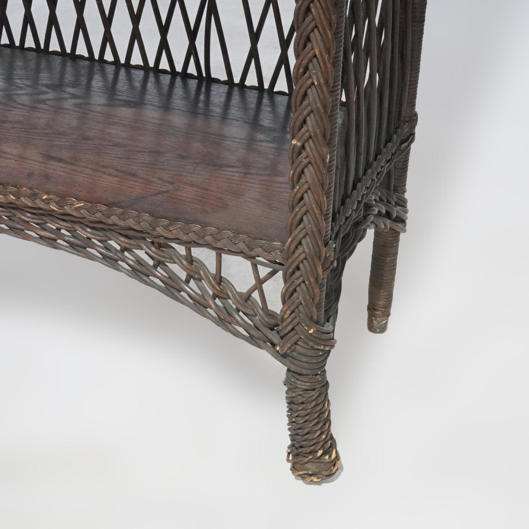 An antique Arts & Crafts book stand in the manner of Stickley offers oak and wicker construction with four shelves and arched apron, circa 1910.

Measures- 48.5''H x 25.75''W x 13.75''D.