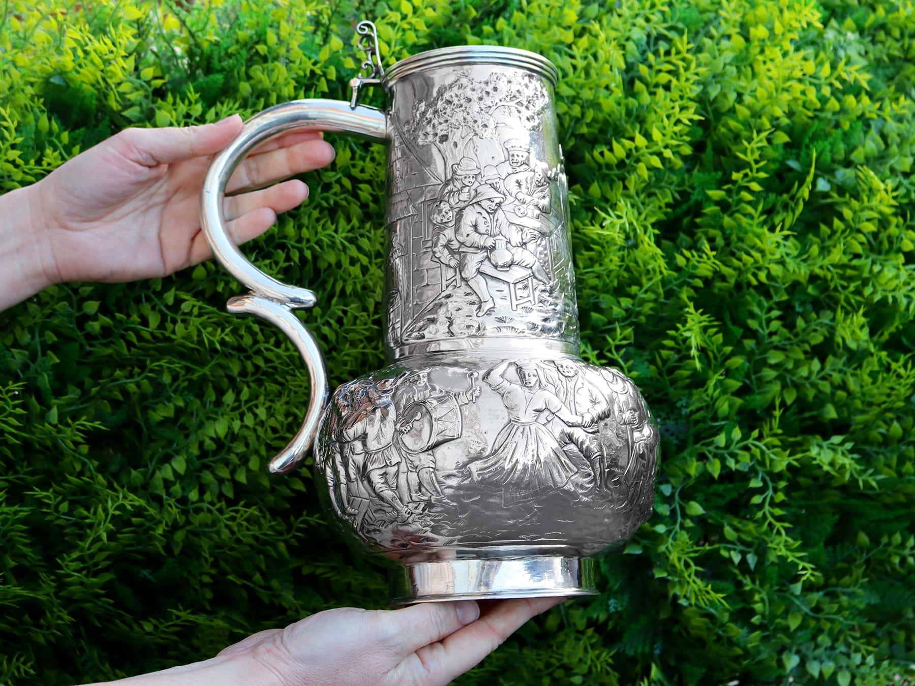 This exceptional antique German silver flagon has a globular body onto a circular spreading foot.

The surface of this German flagon is embellished with exceptional chased decoration depicting figures drinking, conversing and supporting each other