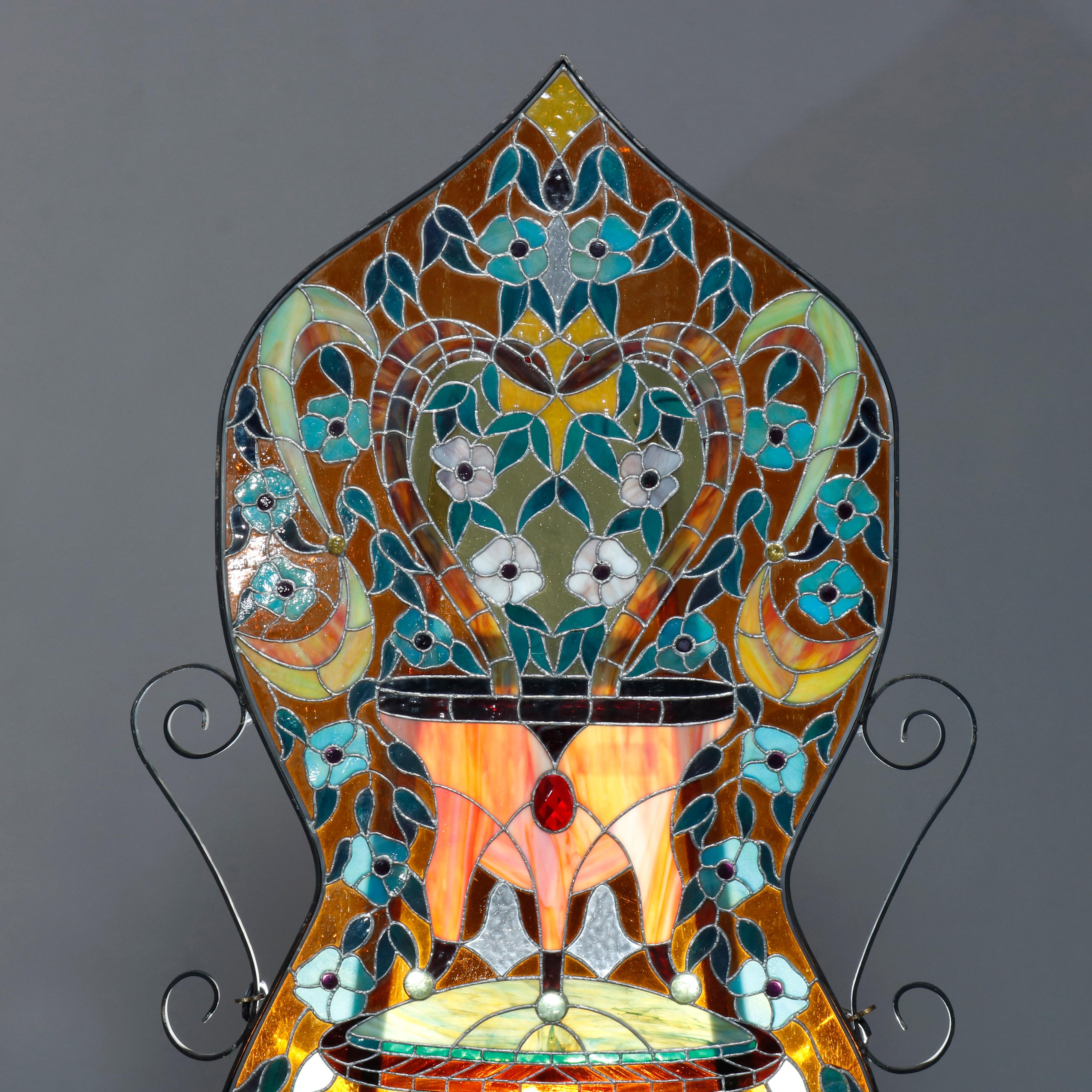An antique Arts & Crafts style garden window offers leaded and jeweled glass with parlor table having floral urn, shaped panel with flanking scroll elements, 20th century.

Measures: 48.25