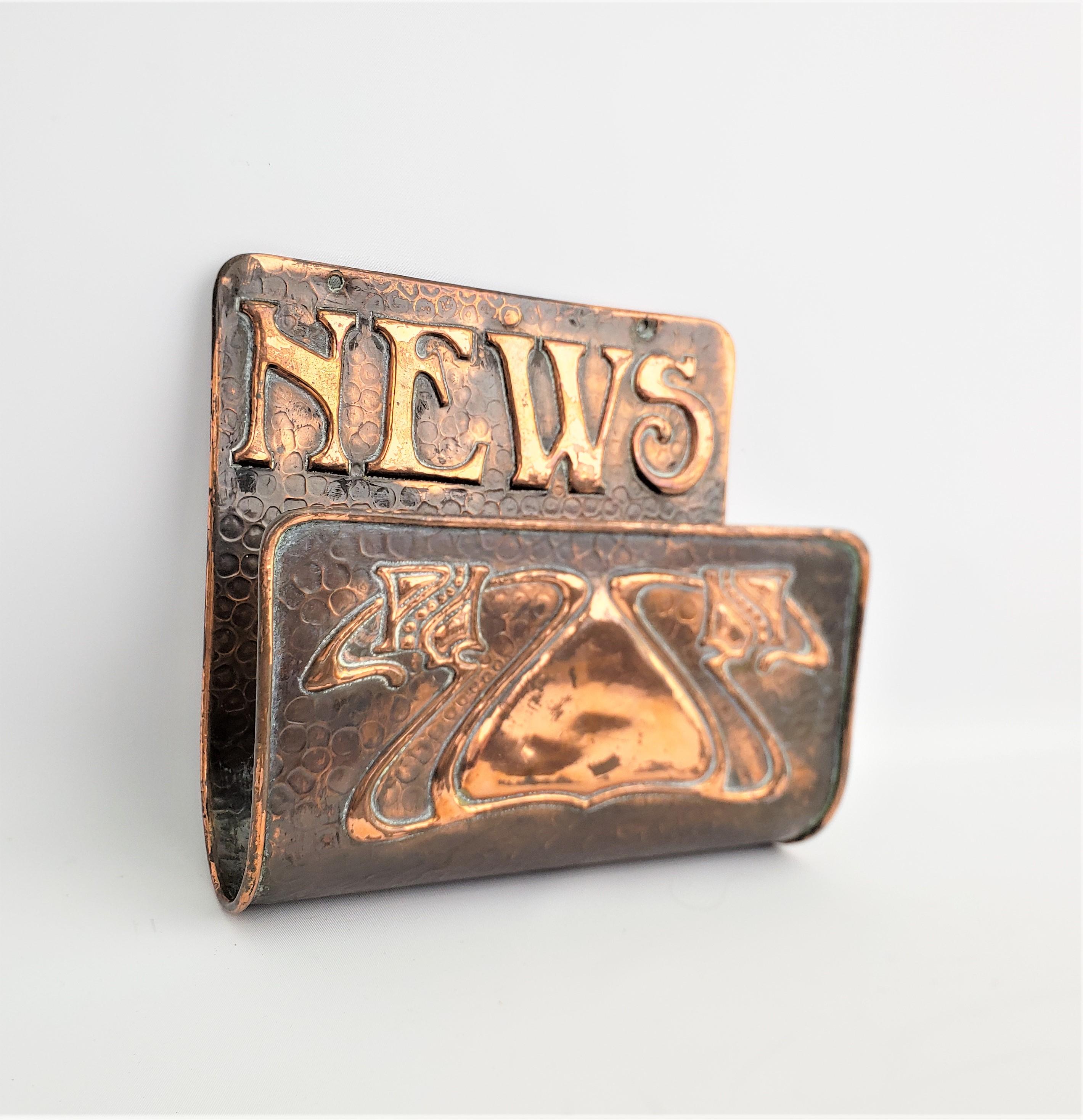 This hand hammered brass newspaper holder is unsigned, but presumed to have been made in the United States in approximately 1920 in an Arts & Crafts style. The rack or holder is constructed of solid brass and has raised letters across the top 