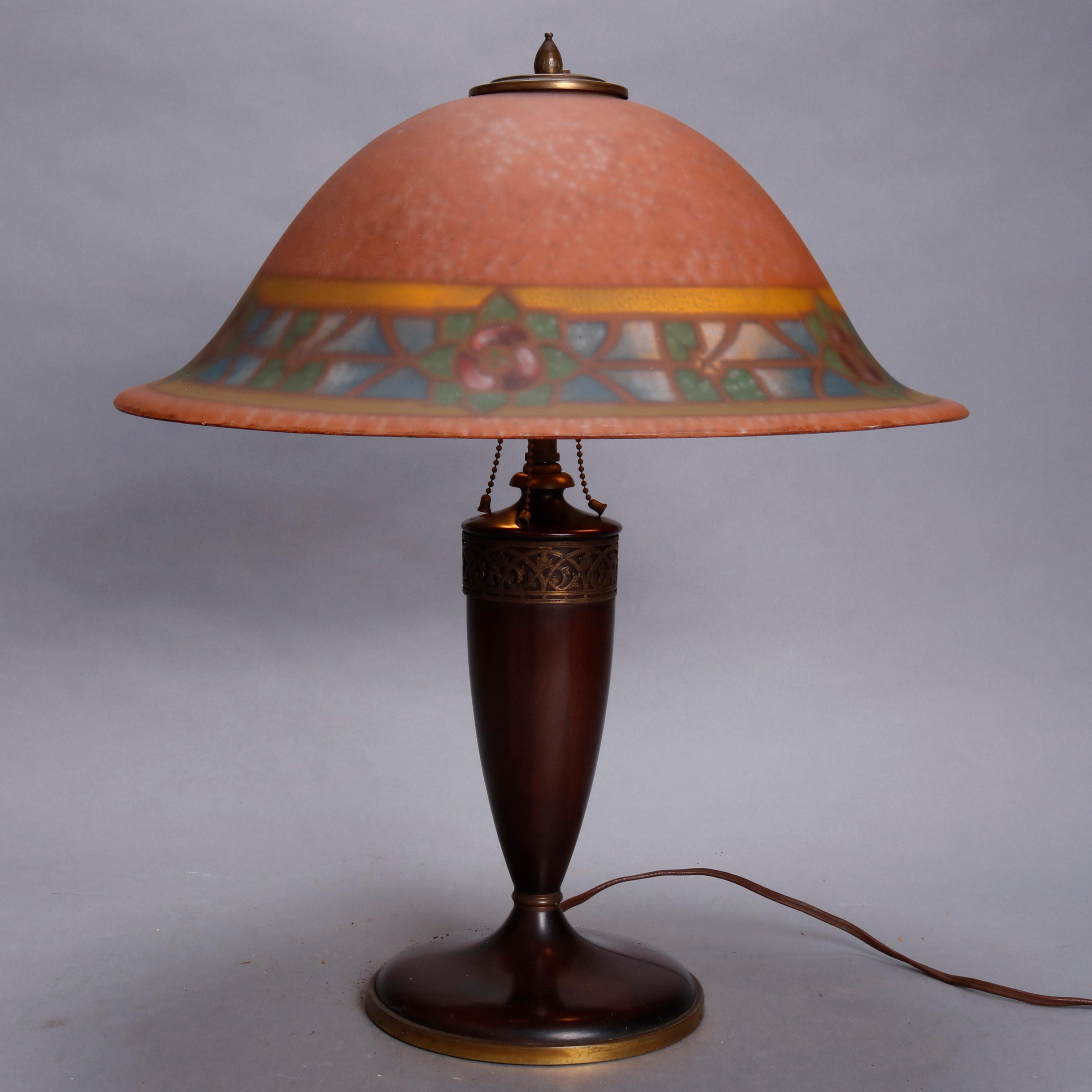 Arts & Crafts pairpoint lamp offer reverse painted bell form shade with stylized floral band over carved wood urn form triple socket base having scroll and foliate cast bronze collar, circa 1910.

Measures: 21.5