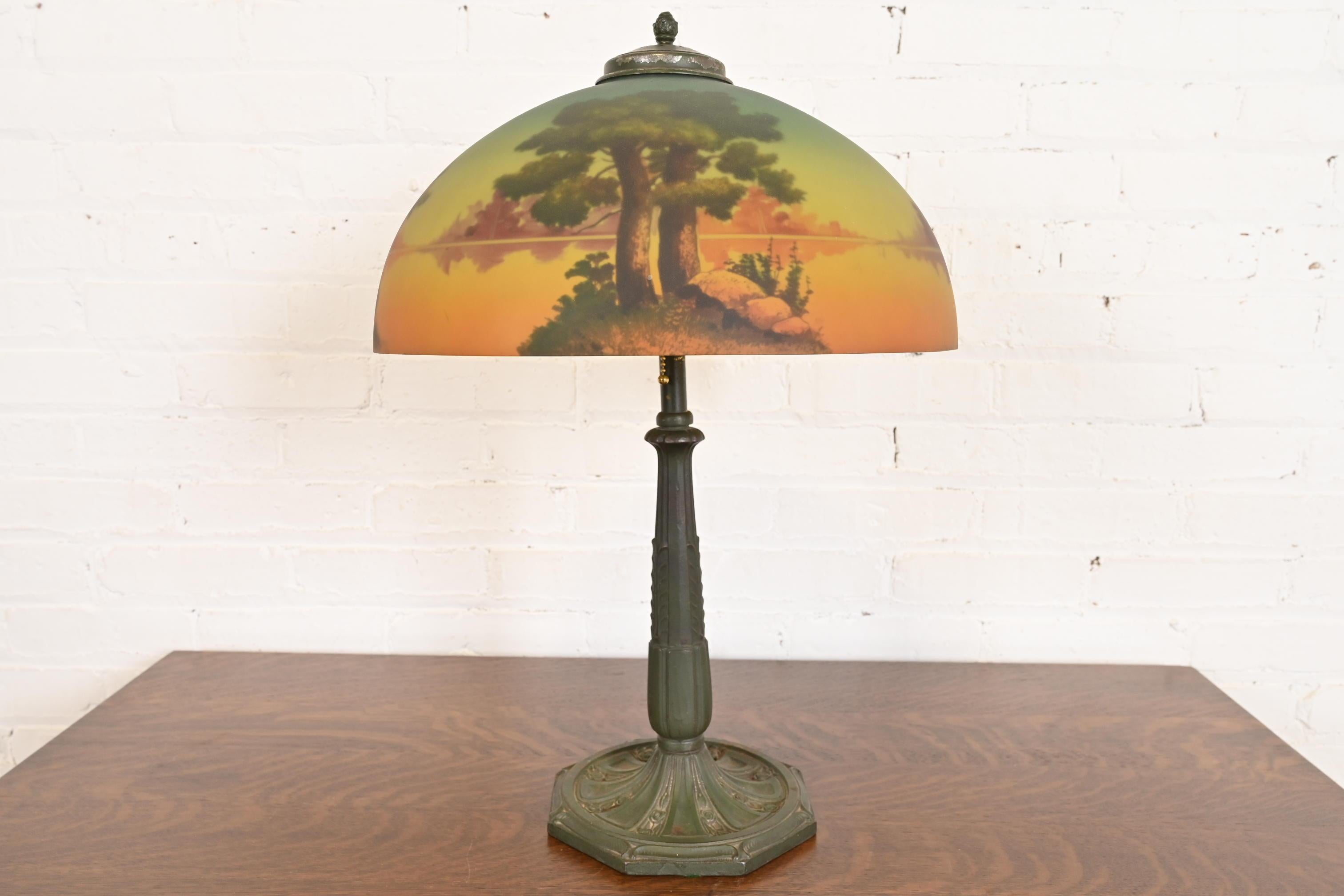 An exceptional antique Arts & Crafts period table lamp with reverse-painted glass dome shade with a lake scene

In the manner of Handel

By Pittsburgh Lamp Co.

USA, Circa 1920s

Measures: 15