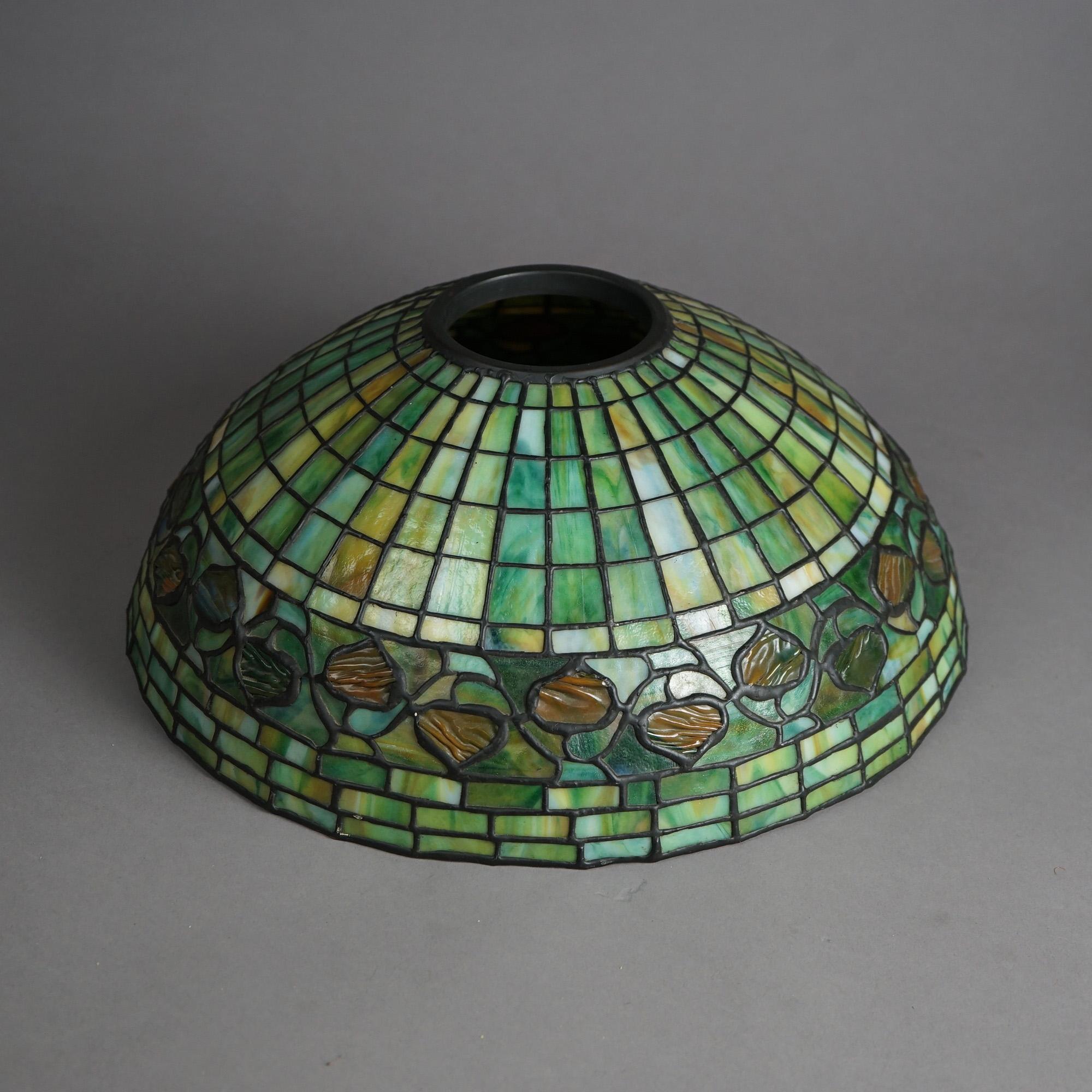 An antique Arts and Crafts lamp shade in the manner of Tiffany offers leaded slag and chunk glass construction in dome form with acorn band, c1910

Measures- 16.5''H x 15.5''W x 15.5''D