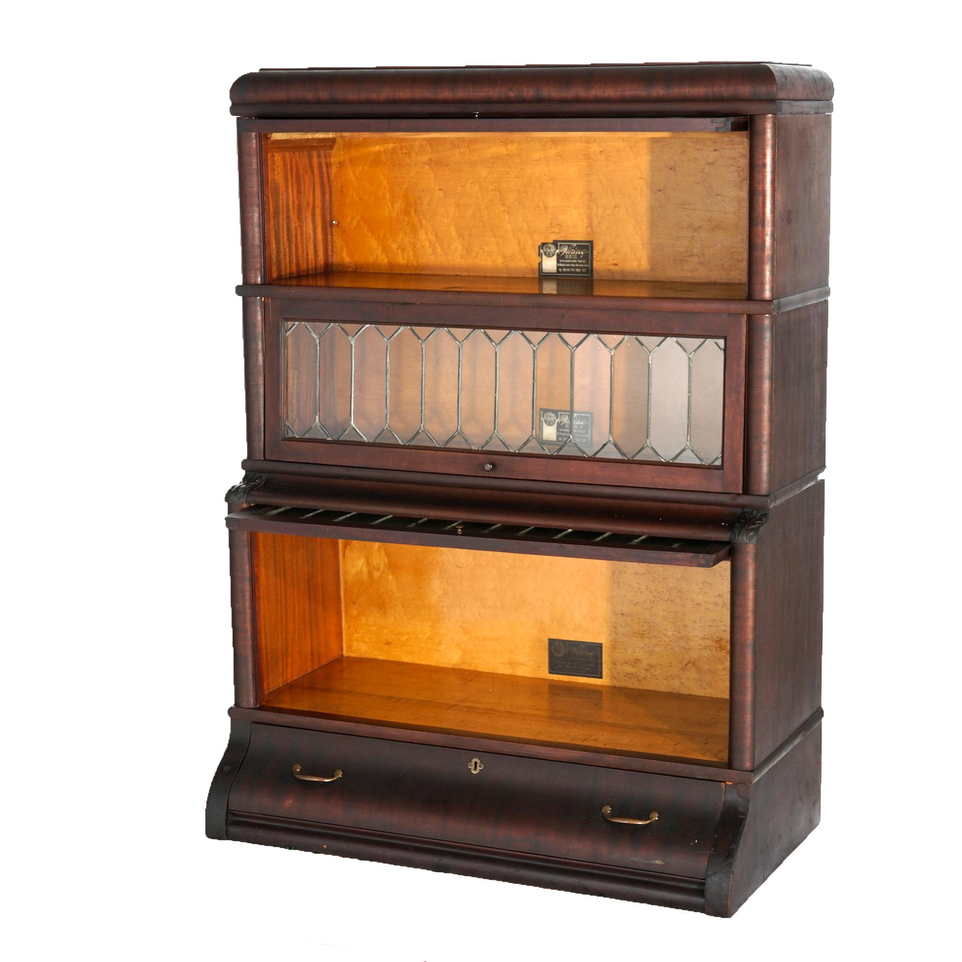 An antique Arts and Crafts barrister bookcase by Viking offers mahogany construction with three stacks, each having leaded glass pull-out doors, seated on ogee base with long drawer, maker label as photograph, c1910

Measures- overall 48.75''H x