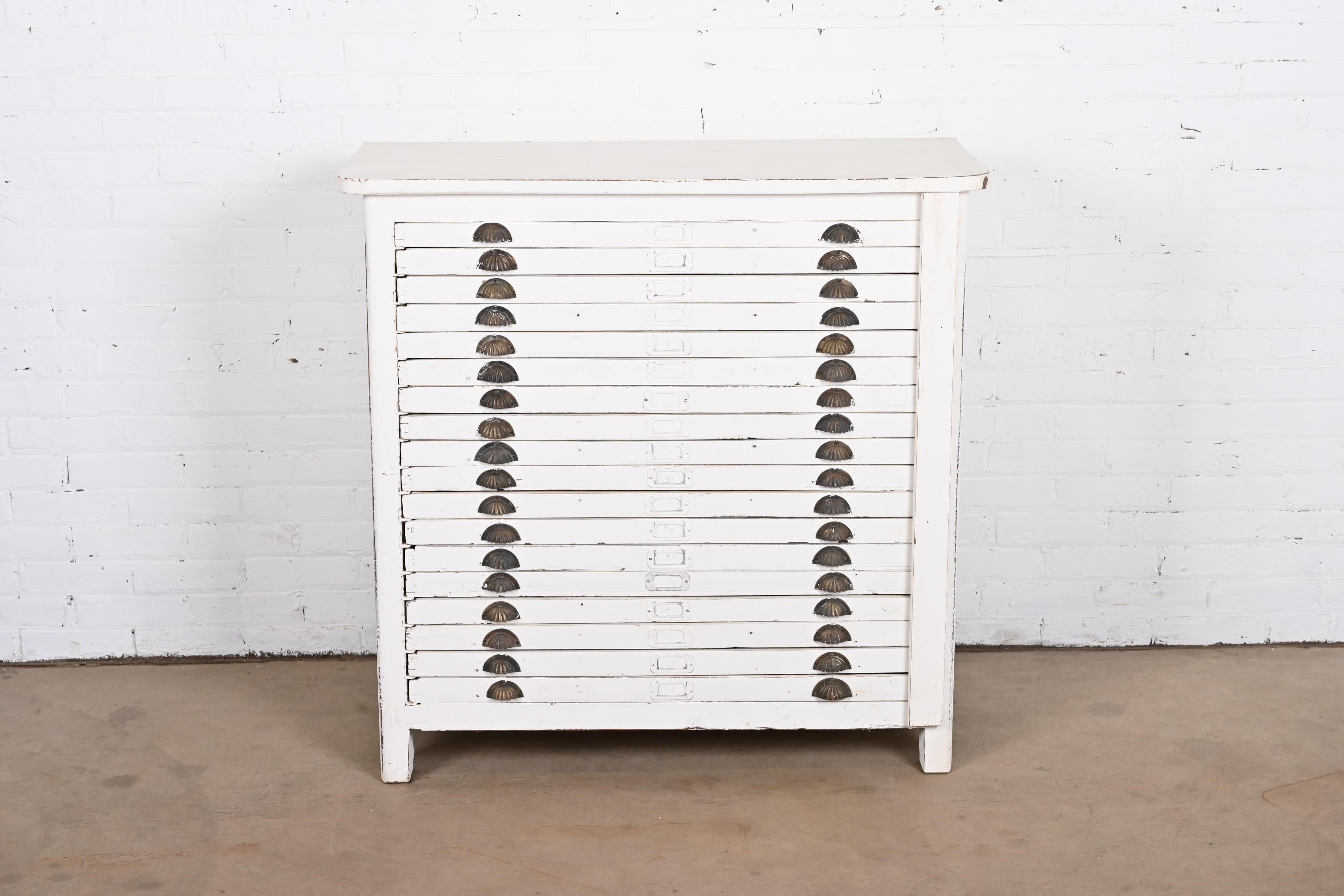 A rare antique primitive Arts & Crafts flat file printer's cabinet

In the manner of Hamilton Manufacturing Co.

USA, Circa 1900

Solid oak in white painted finish, with brass hardware. Eleven drawers with three compartments; four drawers with many