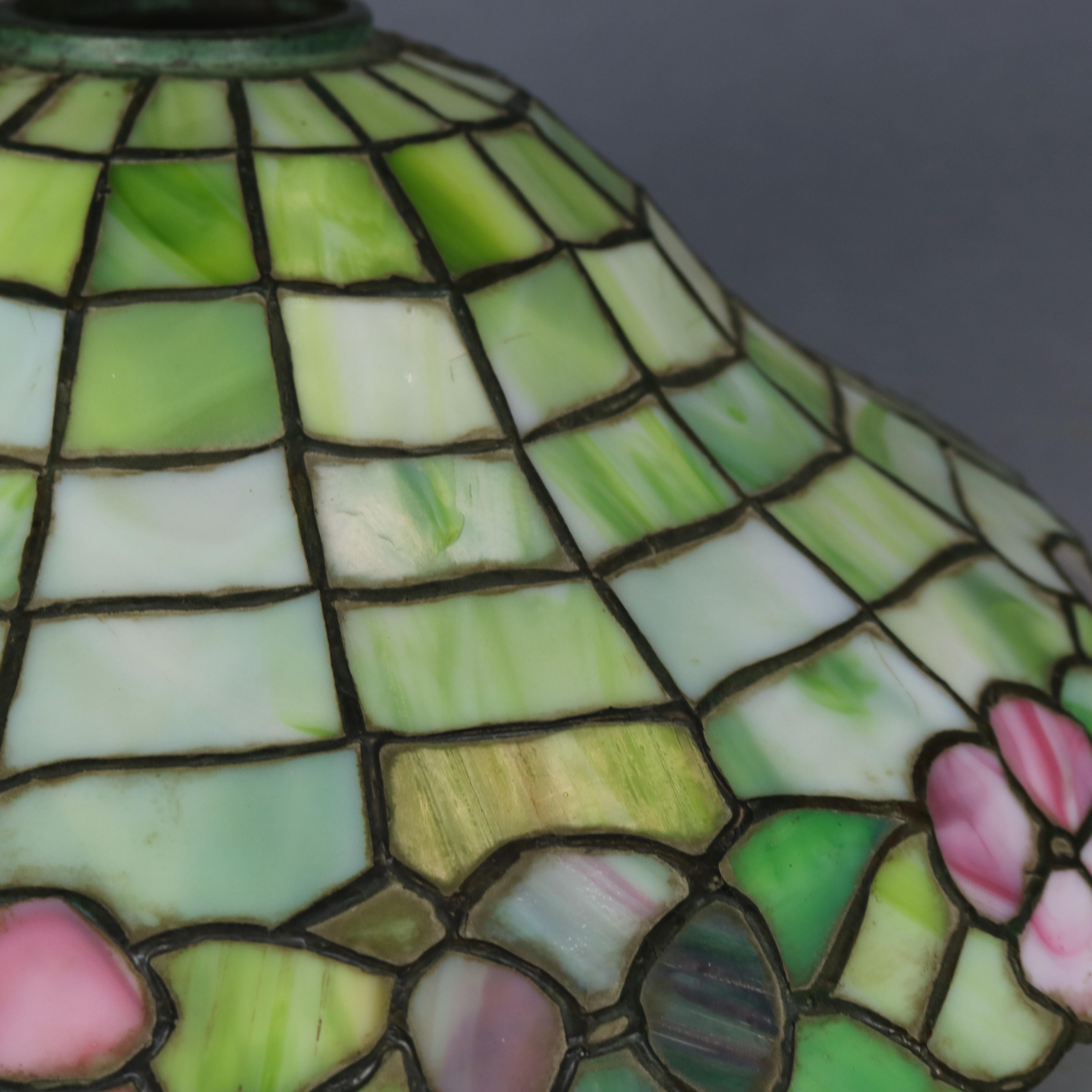 An antique Arts & Crafts table lamp in the manner of Williamson offers leaded stained glass parasol form shade with floral band over a double socket cast base, c1920.

Measures: 20.5