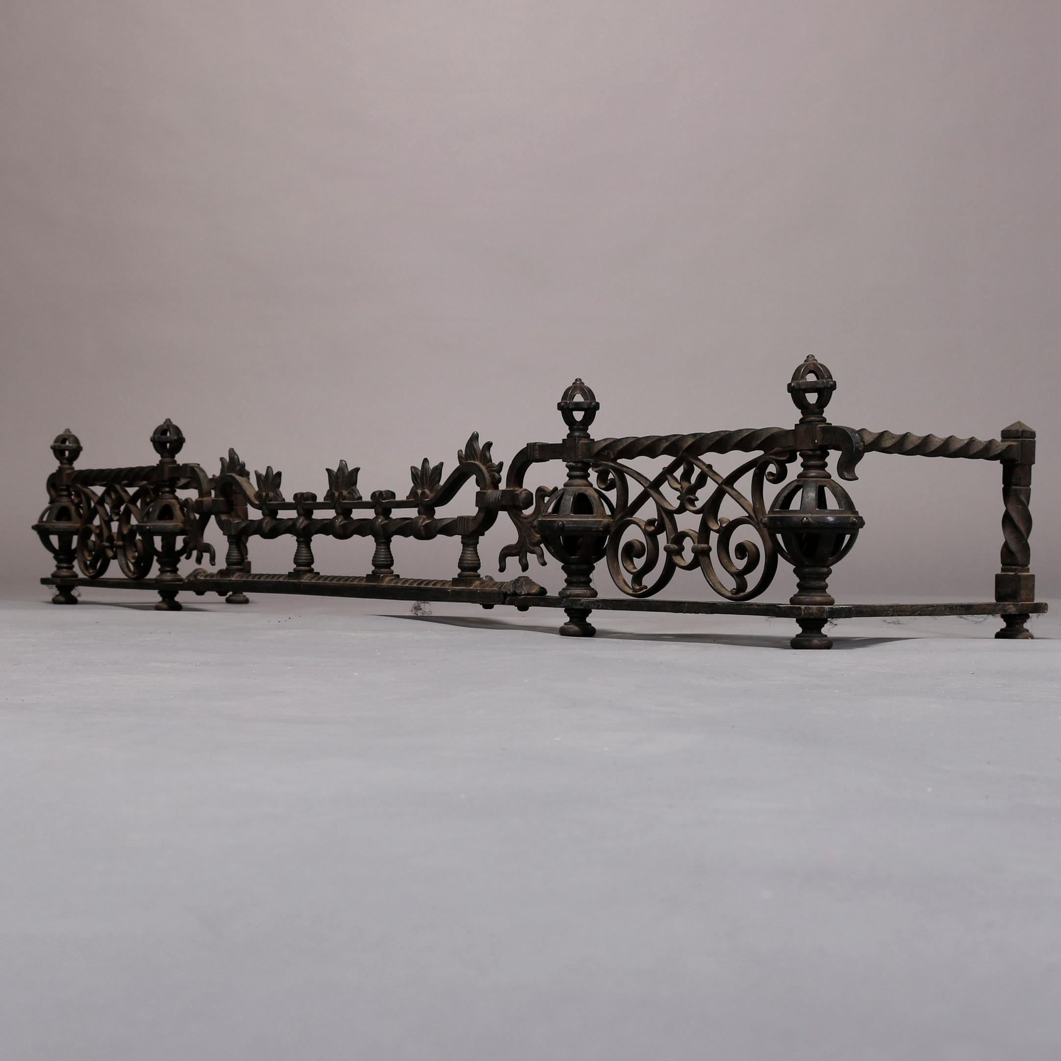 An antique and large Arts & Crafts fireplace fender in the manner of Samuel Yellin offers wrought iron construction with stylized floral, rope twist, spherical, scroll and foliate elements, circa 1900.

Measures: 10