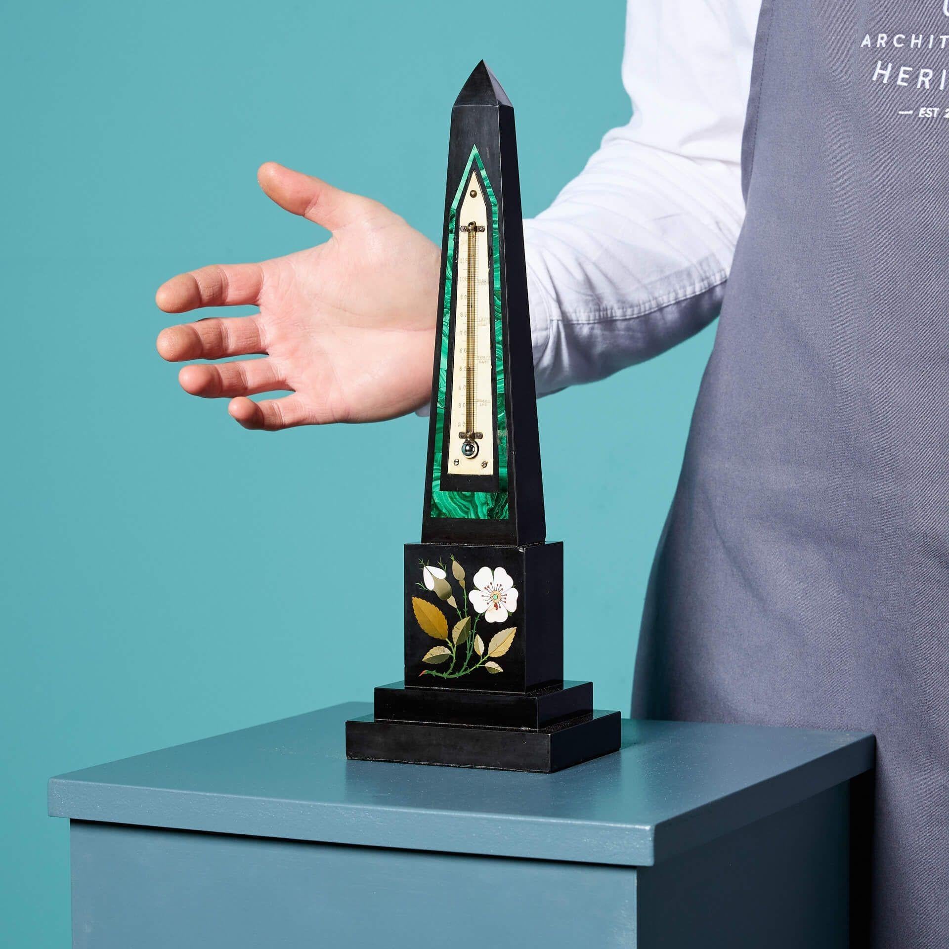 An antique Ashford black marble obelisk from a UK private collection.

This striking obelisk has a centrally mounted ivory register with a malachite surround and a beautiful floral design in pietra dura, fitted with a mercury thermometer in