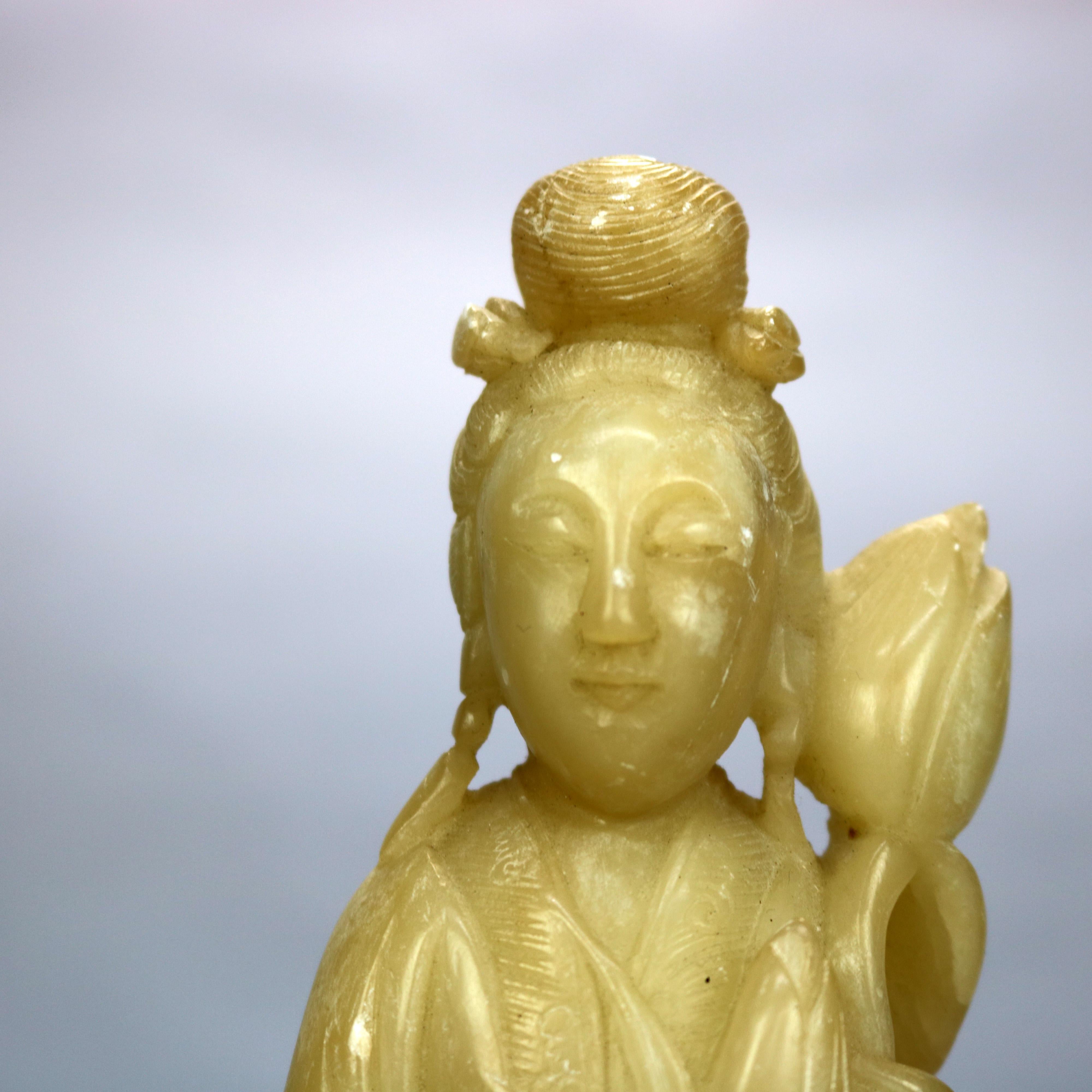 Ein antiker asiatischer Buddha bietet eine geschnitzte Specksteinfigur einer stehenden Frau mit Blume, sitzend auf einem geschnitzten Hartholzsockel, um 1910

Maße: 13.25