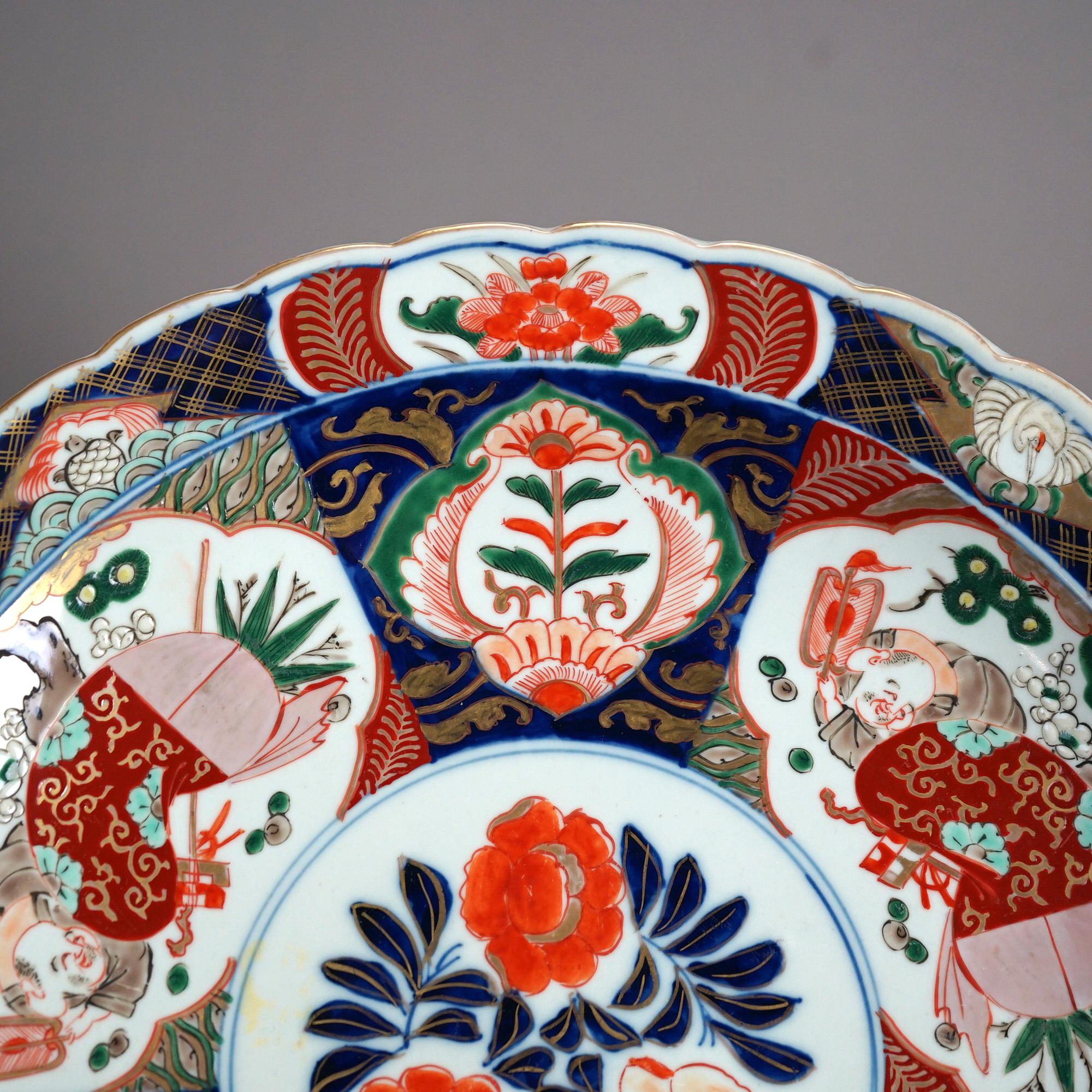 An antique Asian Imari charger offers porcelain construction with hand painted garden reserves, gilt highlights and en verso foliate pattern with central maker stamp, c1920

Measures- 2.25''H x 16''W x 16''D