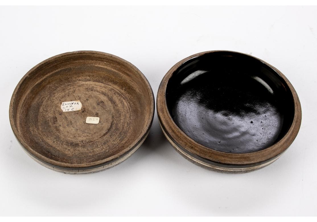 An antique and possibly ancient incised Asian Ceramic Container or Incense Box. The piece with a deep Gray glazed surface incised with intricate floral and scrolling pattern with the interior base having a black glaze. There are  old labels adhered
