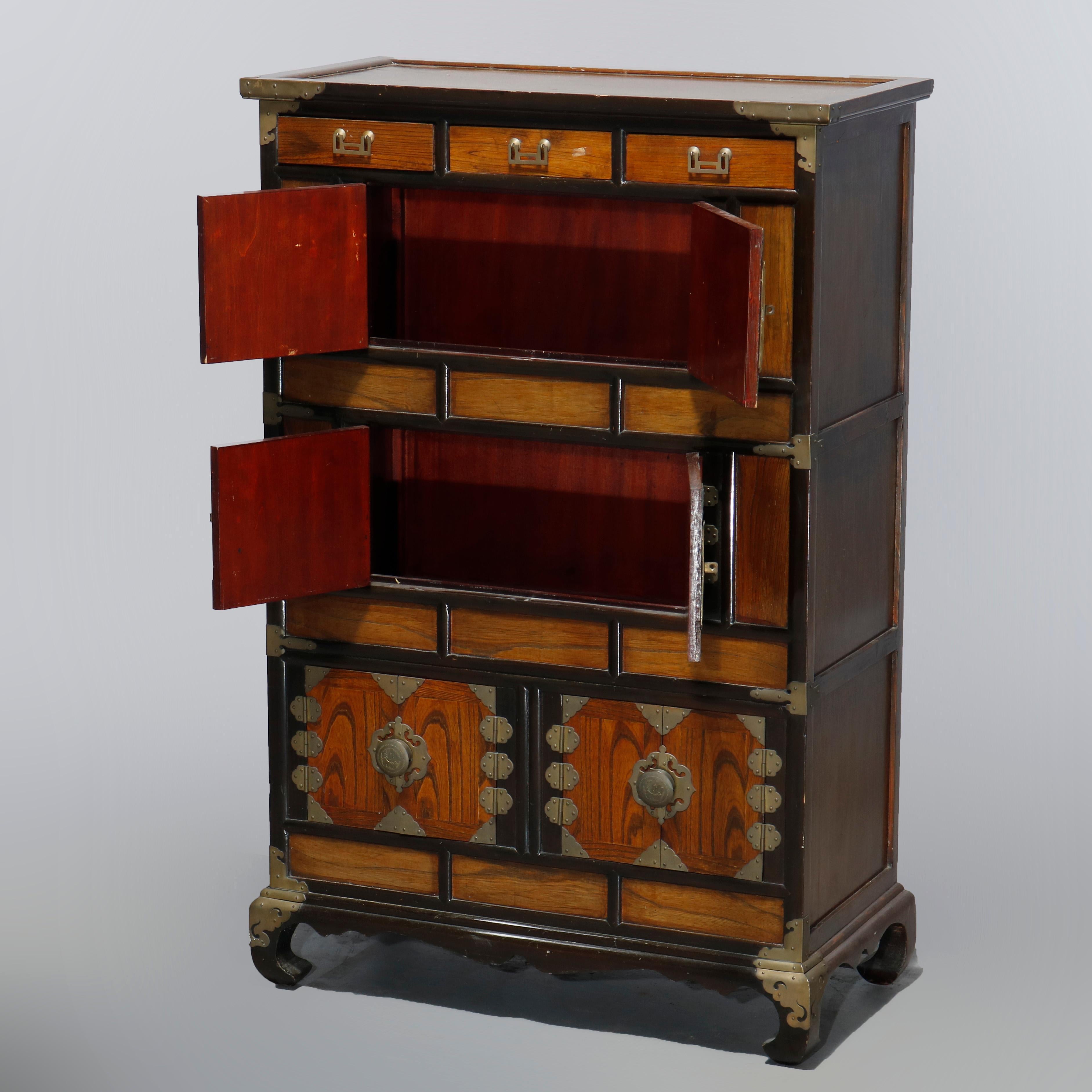 An antique Asian cabinet offers mixed wood construction with multiple drawers and cabinets having brass hinges and hardware throughout, raise on scroll feet, 20th century

Measures: 40.5