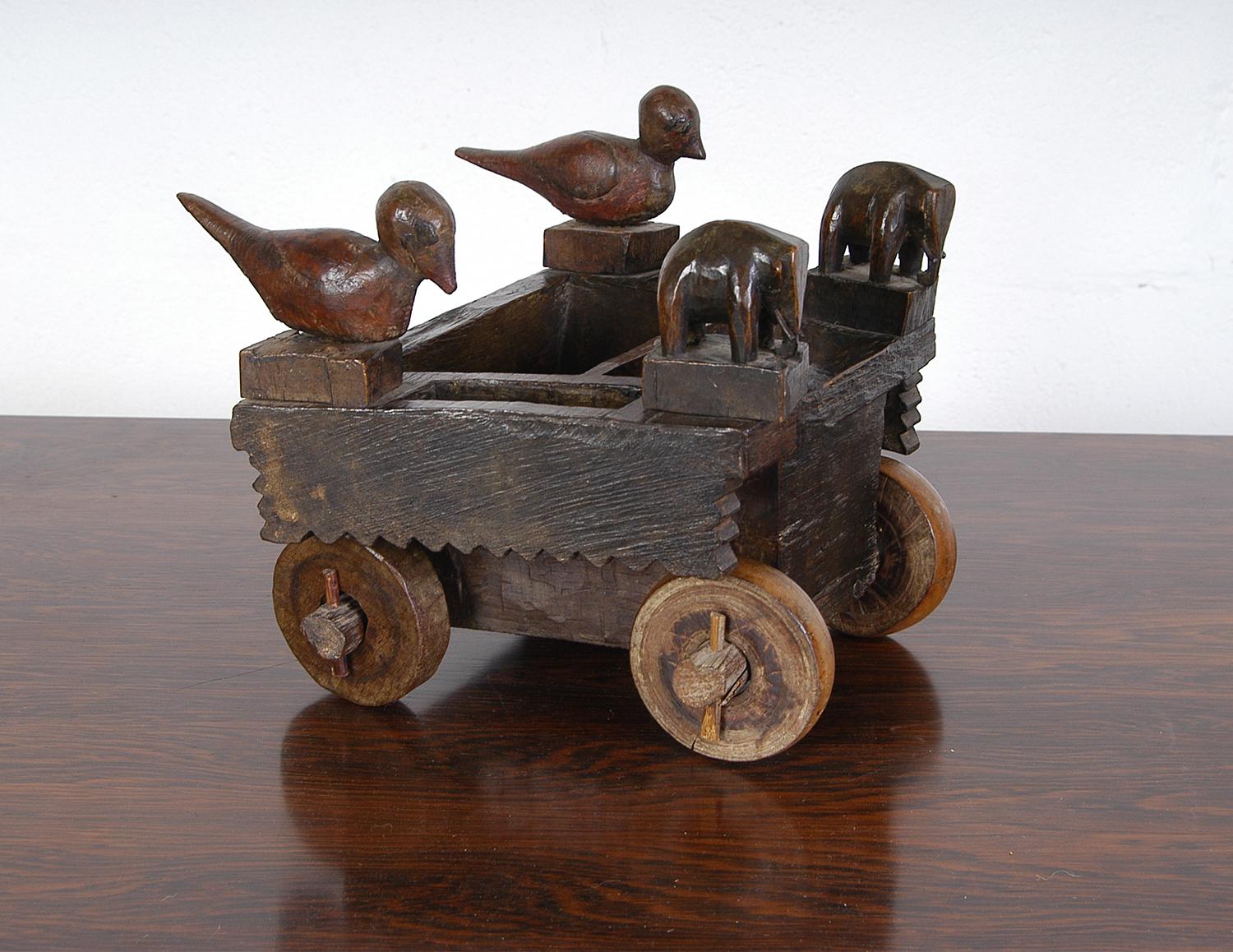 Charming naïve hand-crafted child’s toy decorated with beautifully stylised carved animals in the form of birds and elephants. The birds pivot a little on their wooden dowels and the wheels turn with ease. Judging by the variants in colour it's made
