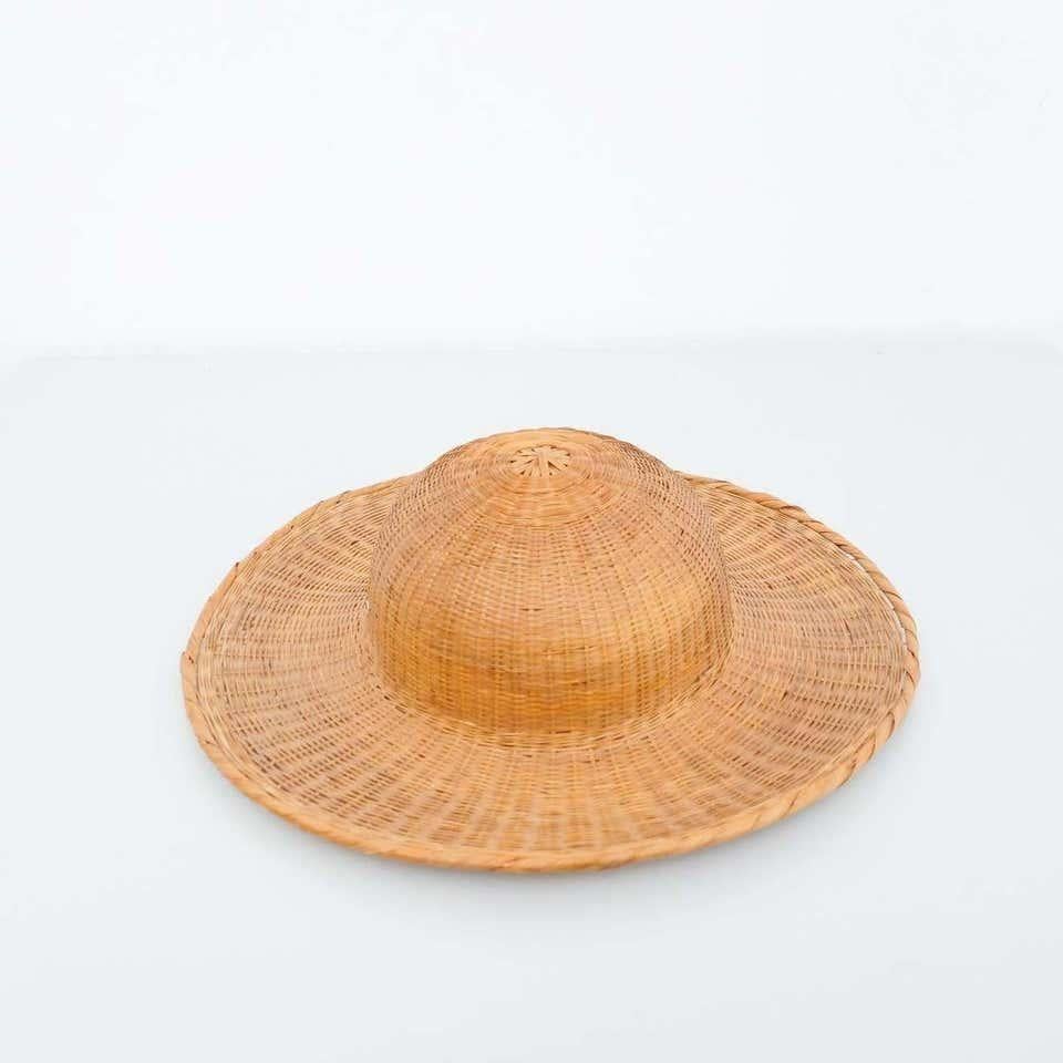 Asian hat, circa 1950.  By unknown manufacturer, from Asia.    In original condition, with some visible signs of previous use and age, preserving a beautiful patina.    Materials:  Rattan    Dimensions:  ø 37.5 cm x H 11 cm.