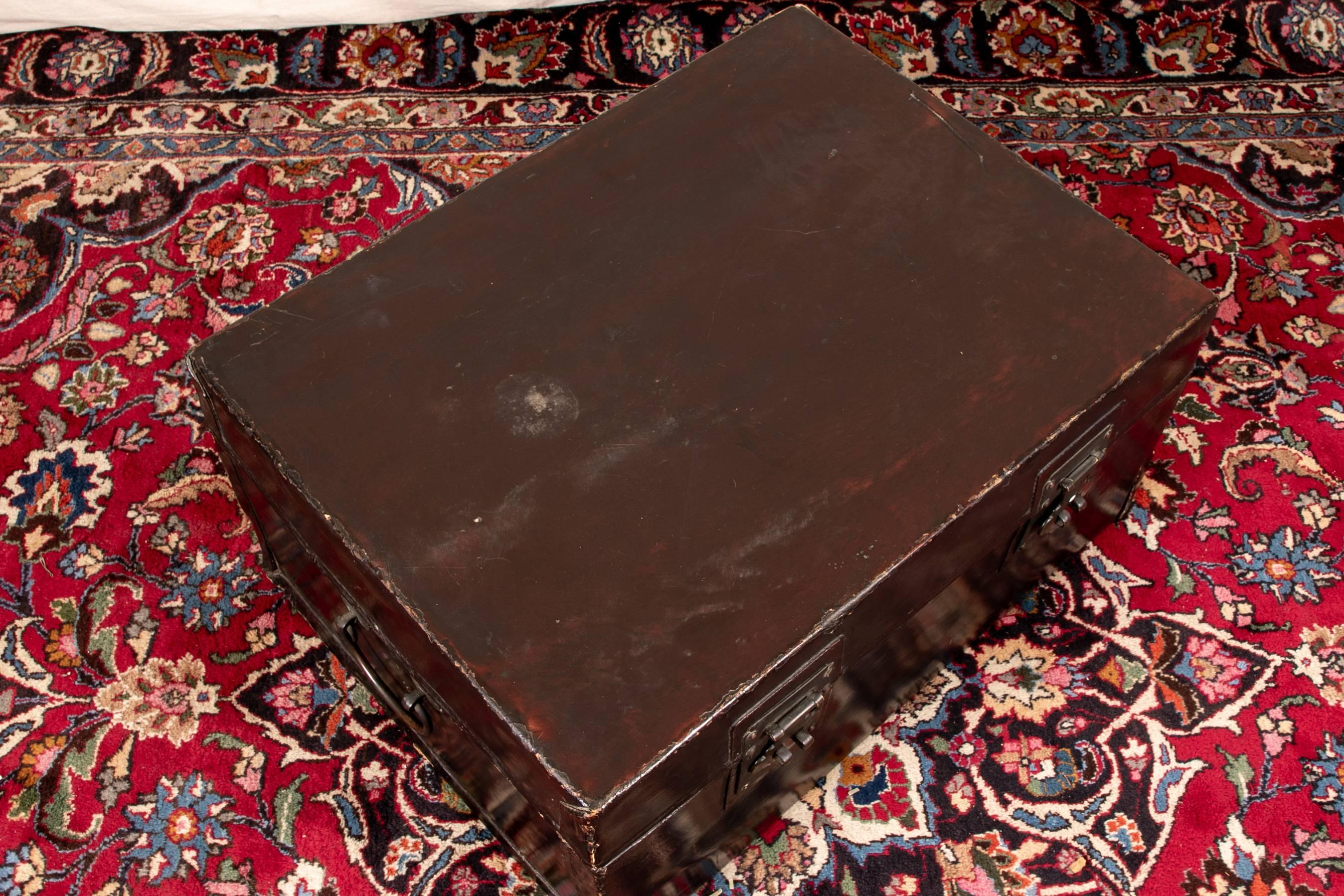 Antique Chinese double lock trunk as a coffee table, lacquer and pigskin in black with an oxblood top with iron hinges, two locks (lacking the pins) and carry handles. In a nice old patina. 

Condition: Expected wear and signs of use including some