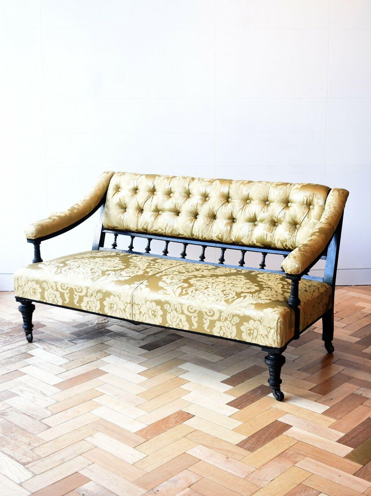 A pretty antique aesthetic movement two seater sofa recently upholstered in a gold Damask print silk fabric. 

This lovely little sofa set is set on its original castors and has a classic aesthetic movement ebonised frame with a charming patina.