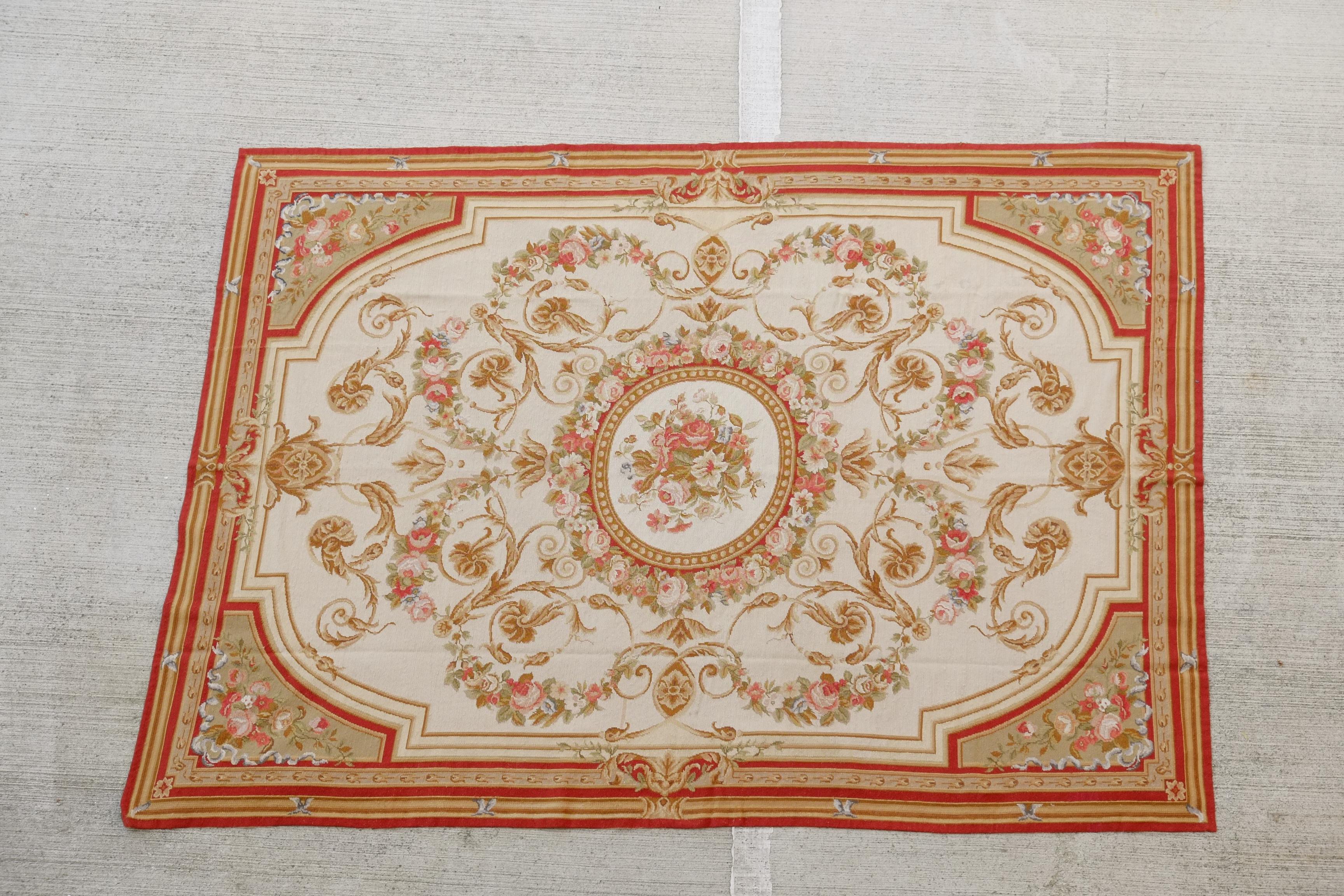 An antique French huge wall hanging or a rug. The wall hanging offers a floral central medallion on a cream ground with a floral spray and border having scroll and foliate decoration, in a palette of rose, gold, and pastels. Circa 1930 to 1950.

A