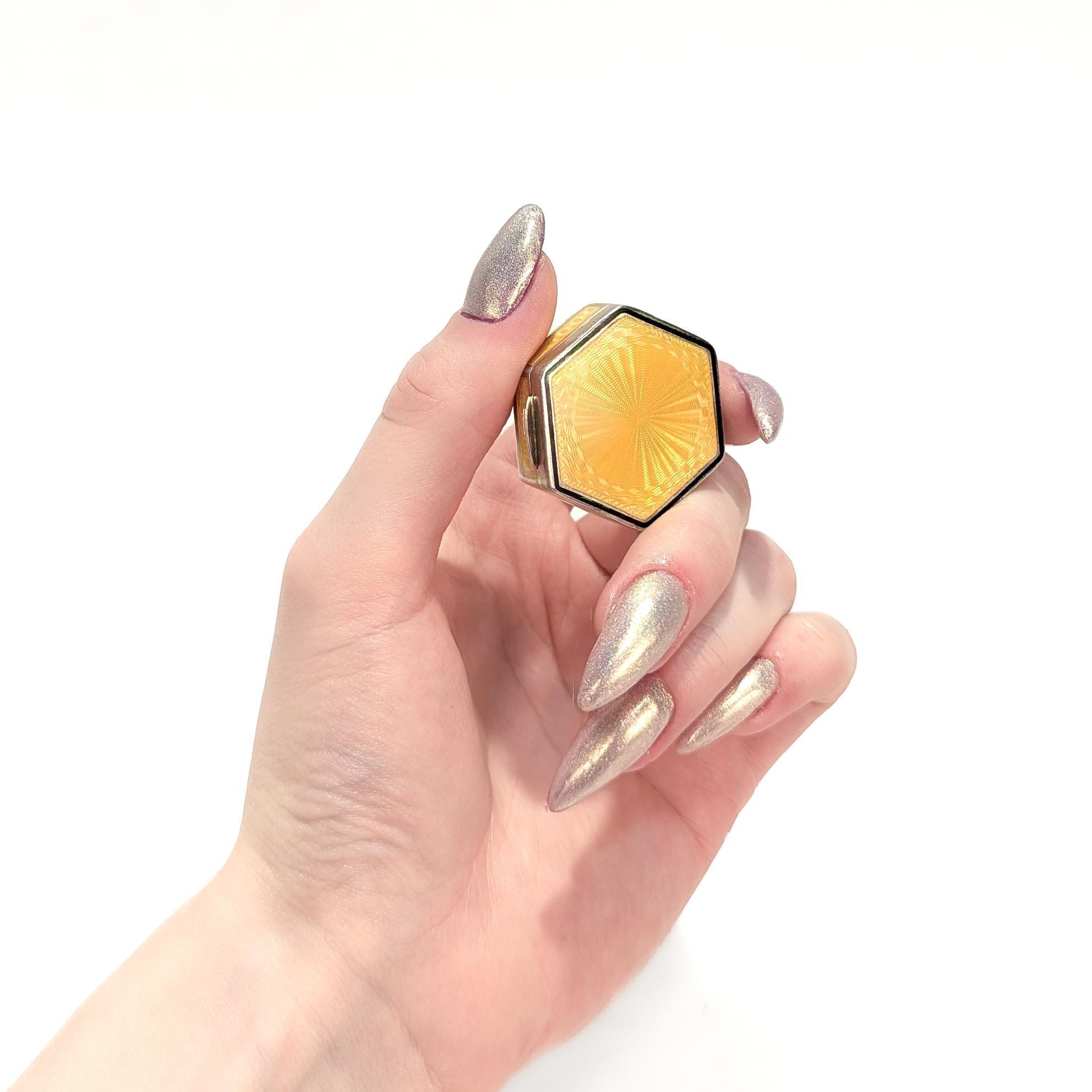 A fine antique Art Deco pill box or compact.

In gilt sterling silver.

In a hexagonal form with yellow guilloche and black line decoration to the lid, guilloche enameling to the sides, and engine turning to the base.

Fully marked to the