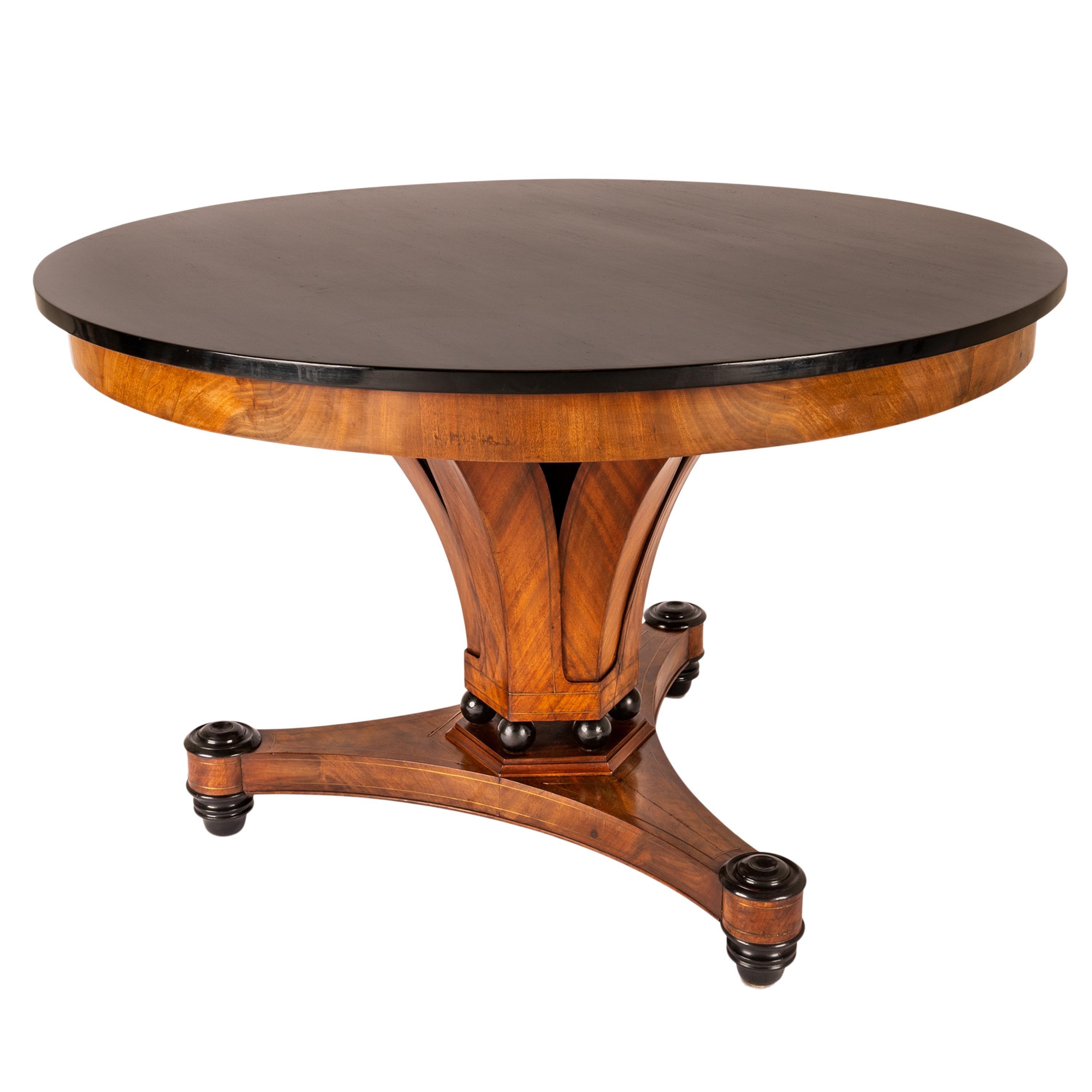 A fine antique Austrian Biedermeier dining or center table, circa 1820.
This very elegant table made from blond walnut and having an ebonized top and ebonized accents, the base with brass line inlay. The circular ebonized top is raised on a flared