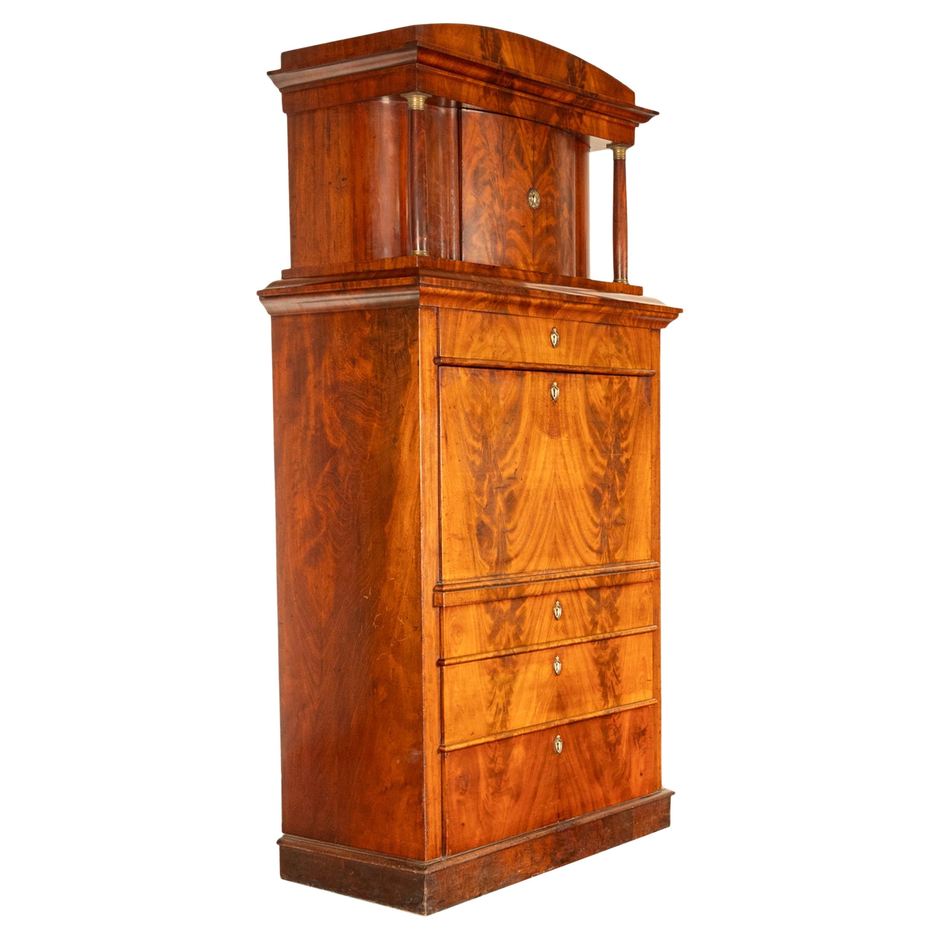 Un raffinato ed elegante mobile da scrivania Biedermeier in mogano austriaco, circa 1820.
Il mobile è diviso in due sezioni, la parte superiore con un frontone architettonico curvo, la parte inferiore è un tabernacolo ad ante curve, affiancato da