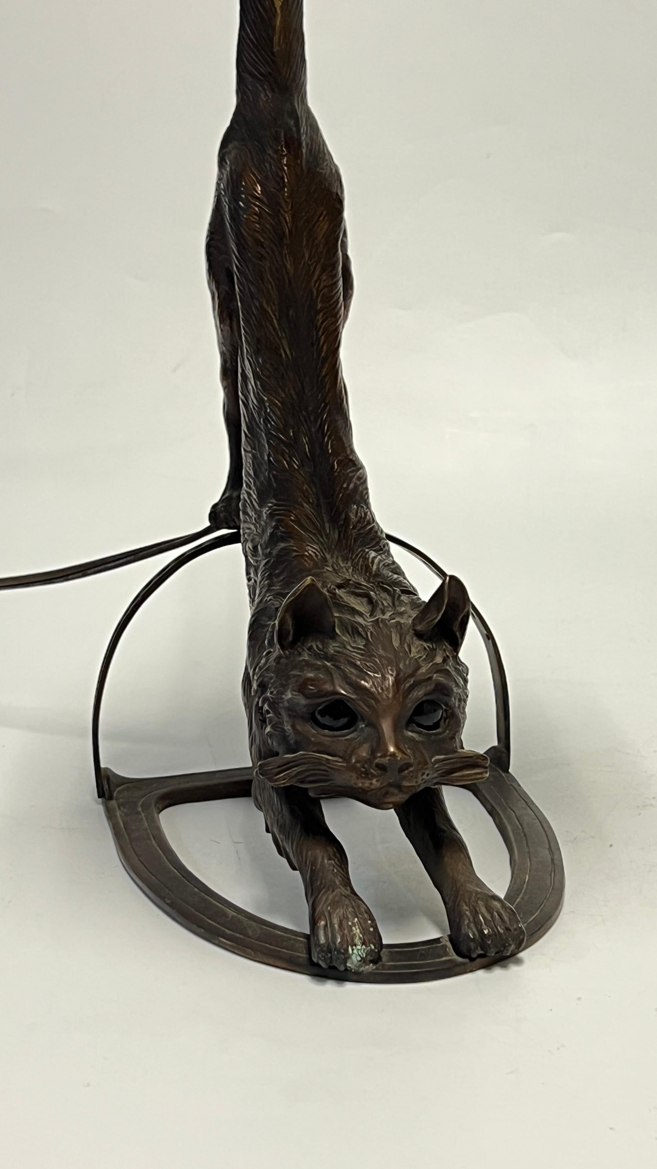 Charming Art Deco period bronze and metal table lamp in the form of a stretching cat, with original porcelain sockets and modern cord and plug with two on settings that light the cat's green eyes.  Apparently unsigned.