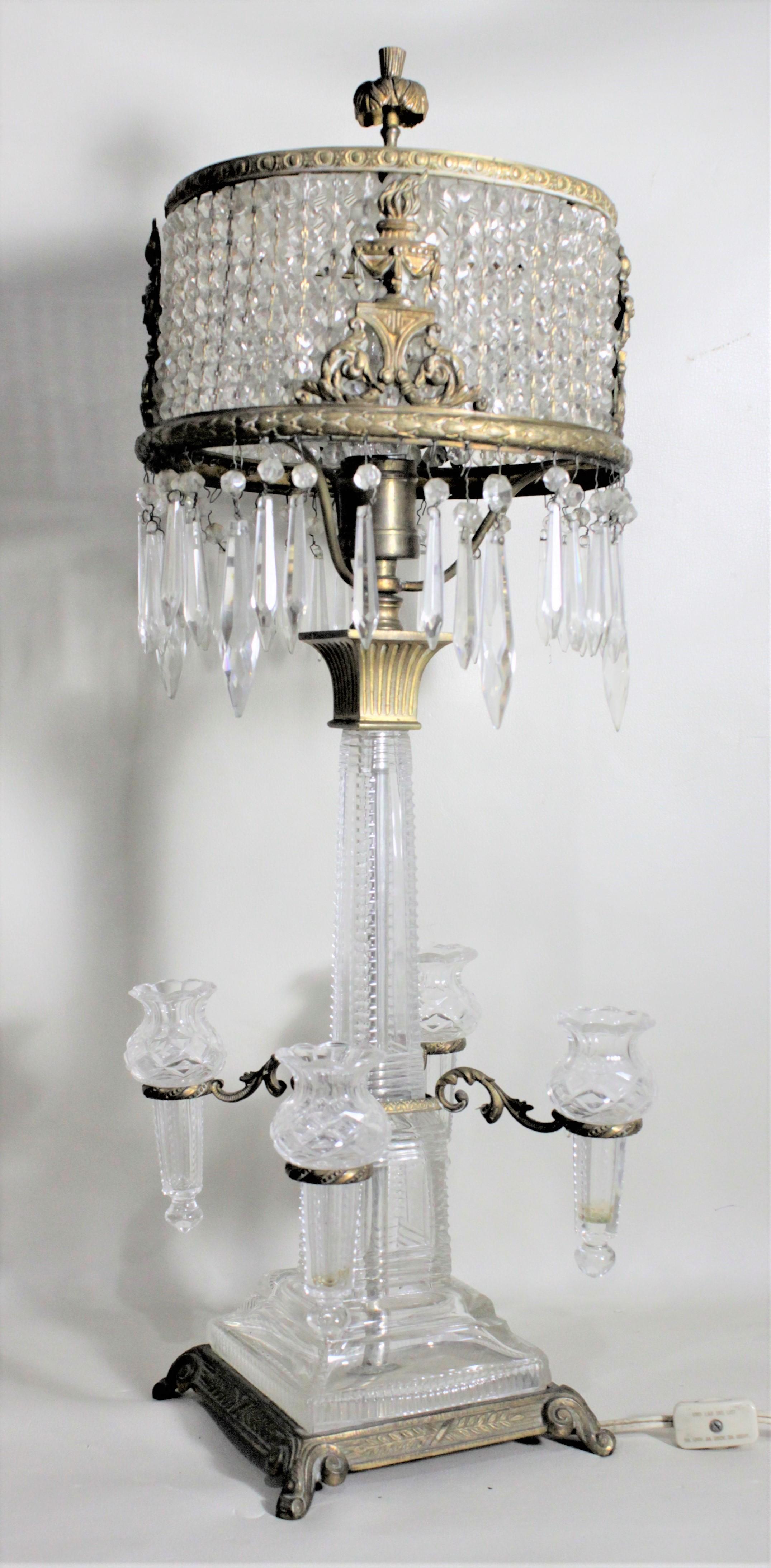 This very unique antique crystal lamp is unsigned, but presumed to have been made in Continental Europe, most likely Austria, in circa 1900 in the period Edwardian style. This lamp is composed of cut glass and crystal with gilt finished cast metal