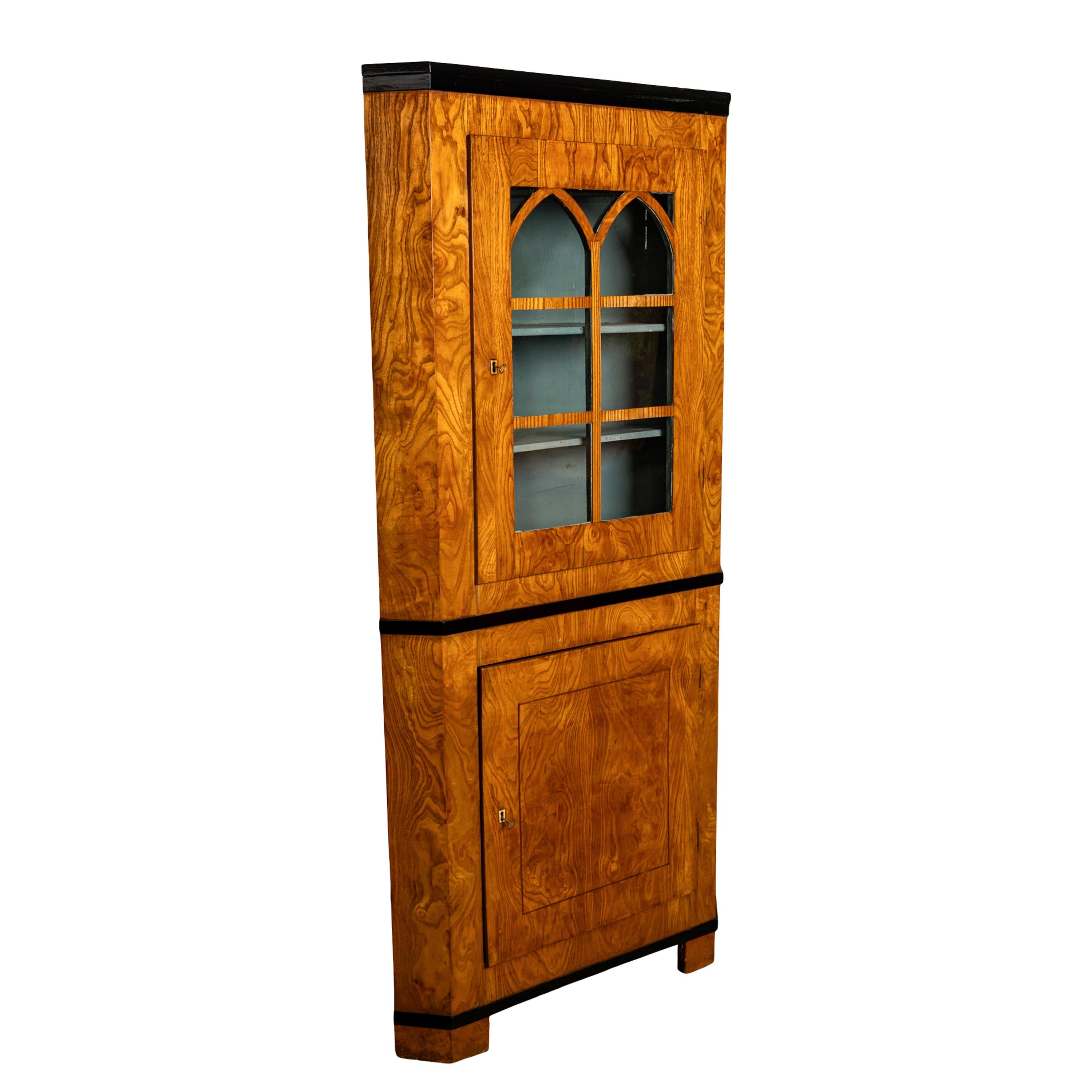 A very stylish antique Austrian Biedermeier figured Ash corner cabinet, circa 1830.
The cabinet with an ebonized crown and a glazed door below with arched panels, the door enclosing three shelves and the interior having the original grey paint. To