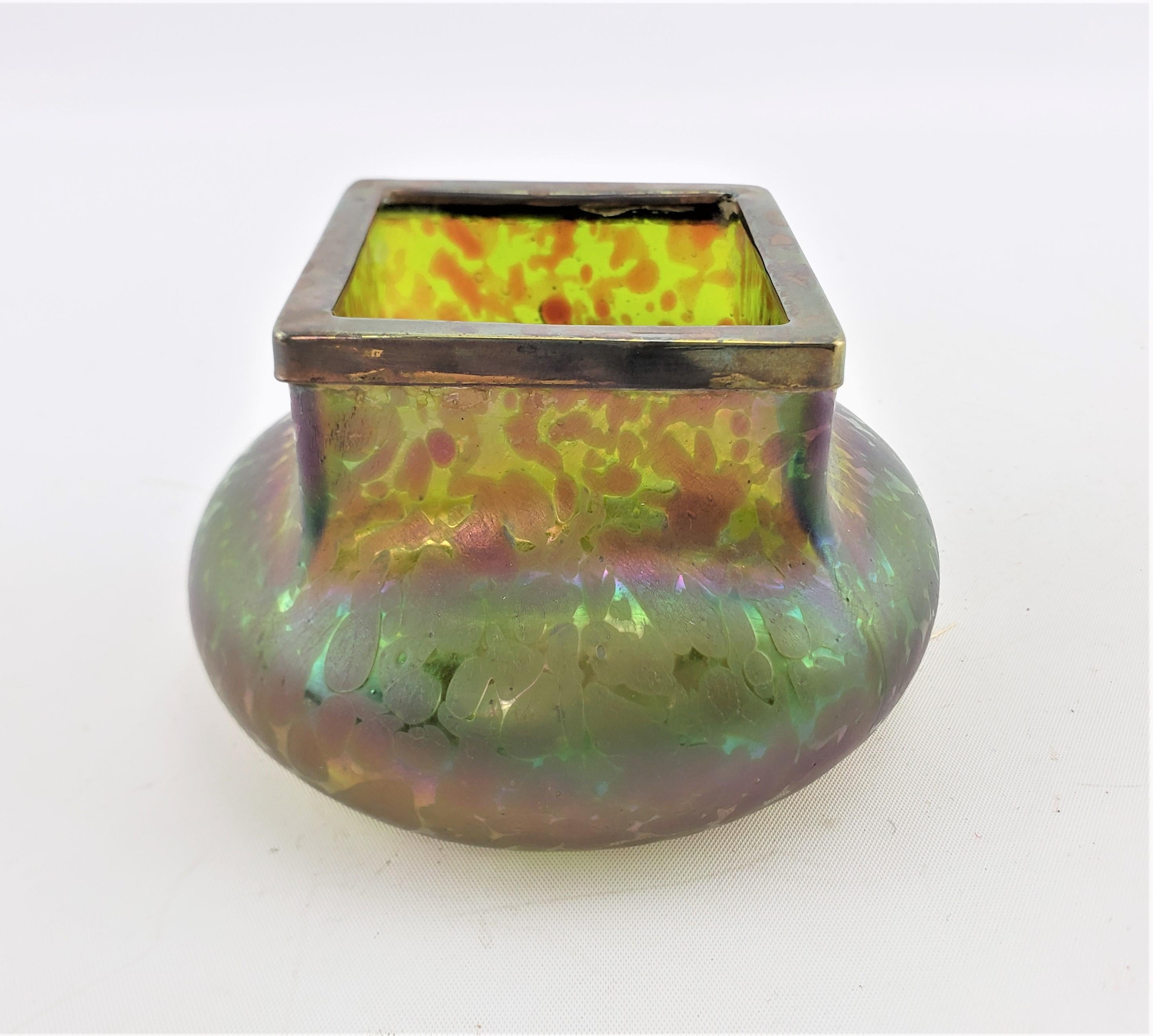This antique art glass vase is unsigned, but presumed to have originated from Austria and dates to approximately 1900 and done in the period Art Nouveau style. The vase is done in multi colors with strong iridescence with a squared top and bulbous