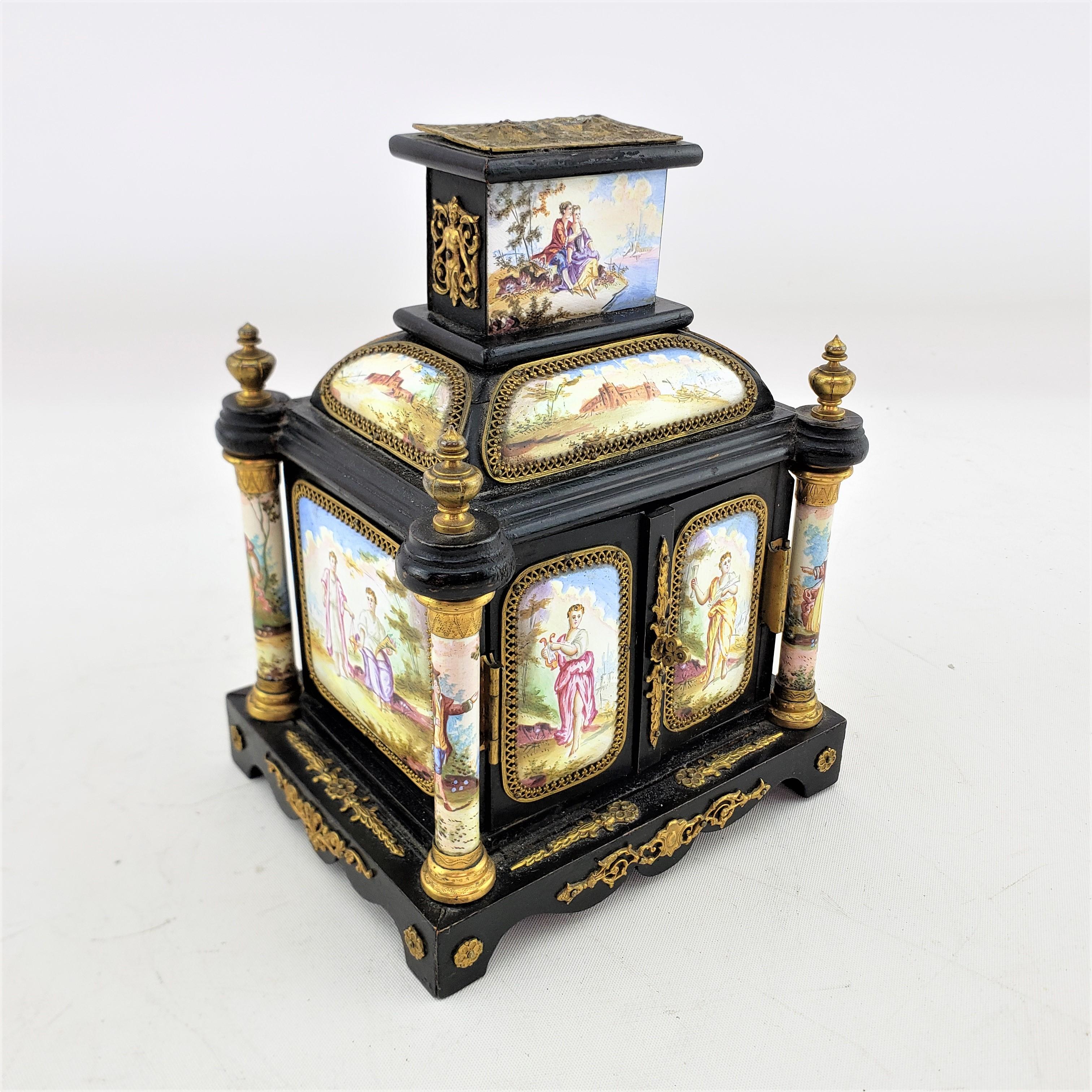 This antique miniature cabinet is unsigned, but presumed to have originated from Austria and date to approximately 1880 and done in a Romantic style. The box is composed of a softwood with a black painted finish with applied hand painted enamel