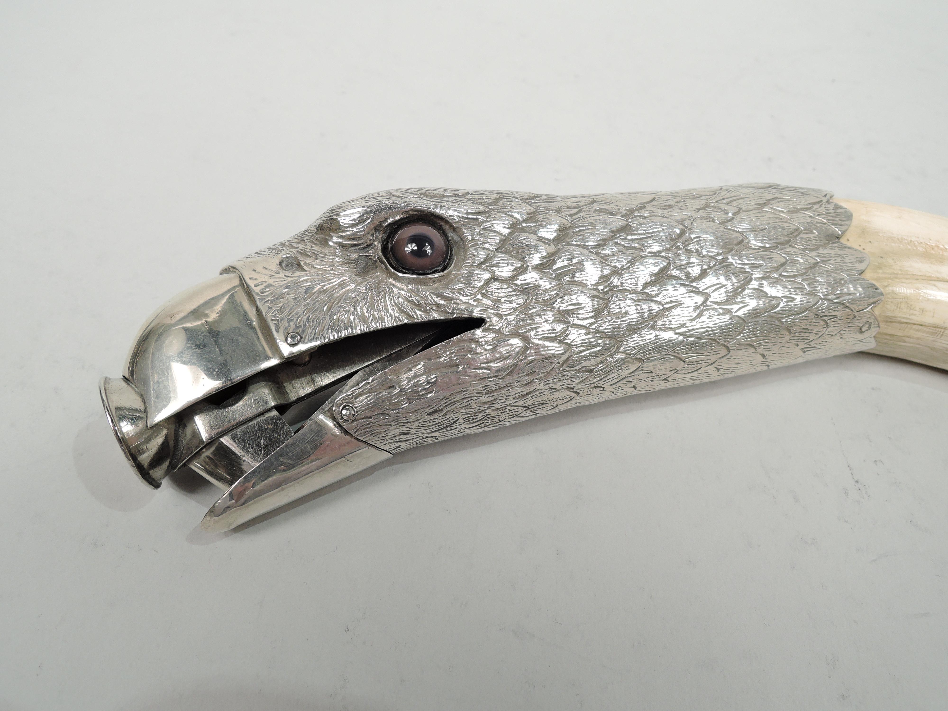 Austrian cigar cutter, circa 1900. Eight-hundred silver eagle head with penetrating glass eyes and dense imbricated feathers. Insert in beak ring and snap goes the jaw! Mounted to boar tusk, which is not at all the same as a bore’s tusk. Guaranteed