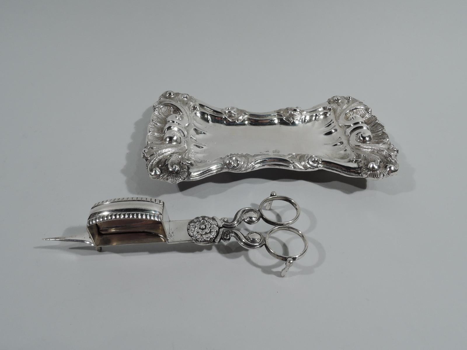 Austrian Rococo silver candle snuffer, 1827. Hinged with flower-head mount and flat vertical blade that fits into rectangular box with curved and lobed top. Ring handles on s-scroll mounts. Three baluster supports. Marks include year and alloy,