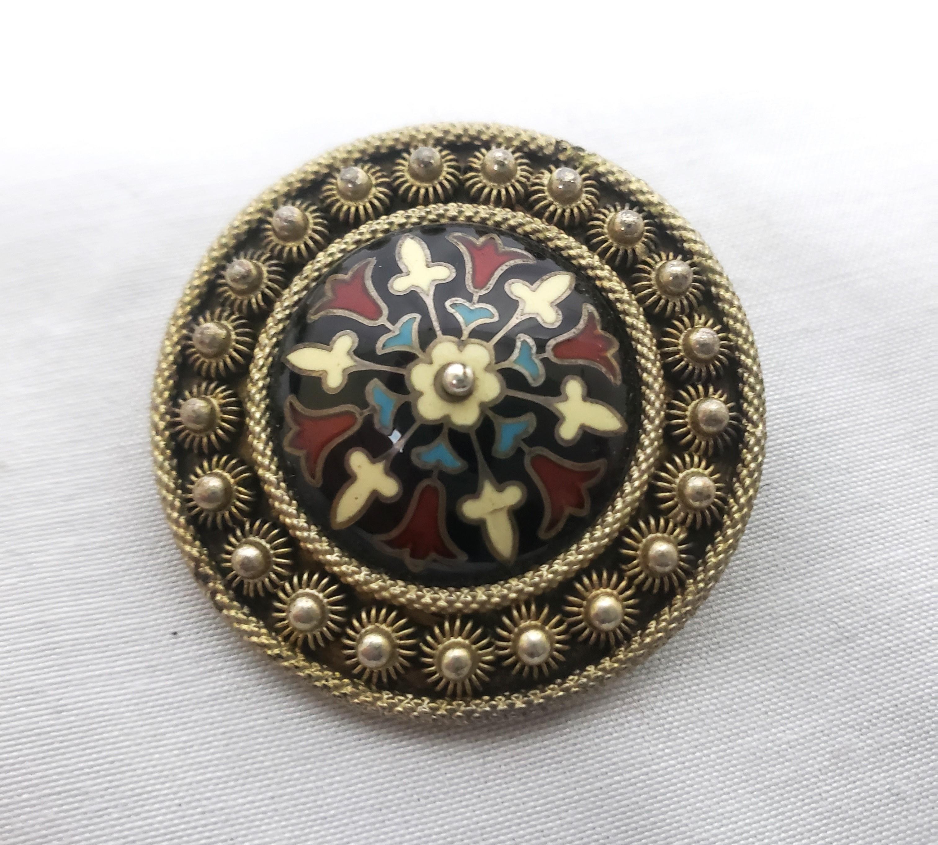 This antique brooch is hallmarked by an unknown maker and presumed to have originated from Austria and date to approximately 1900 and done in a period Art Nouveau style. The brooch is composed of silver with ornate enamel decoration with a stylized